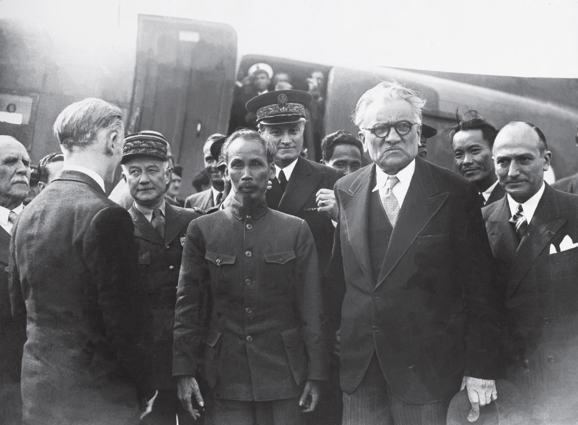 Photo of French diplomat Marius Moutet, Vietnamese President Ho Chi Minh, and their associates in France. The plane President Ho Chi Minh arrived on is pictured in the background.