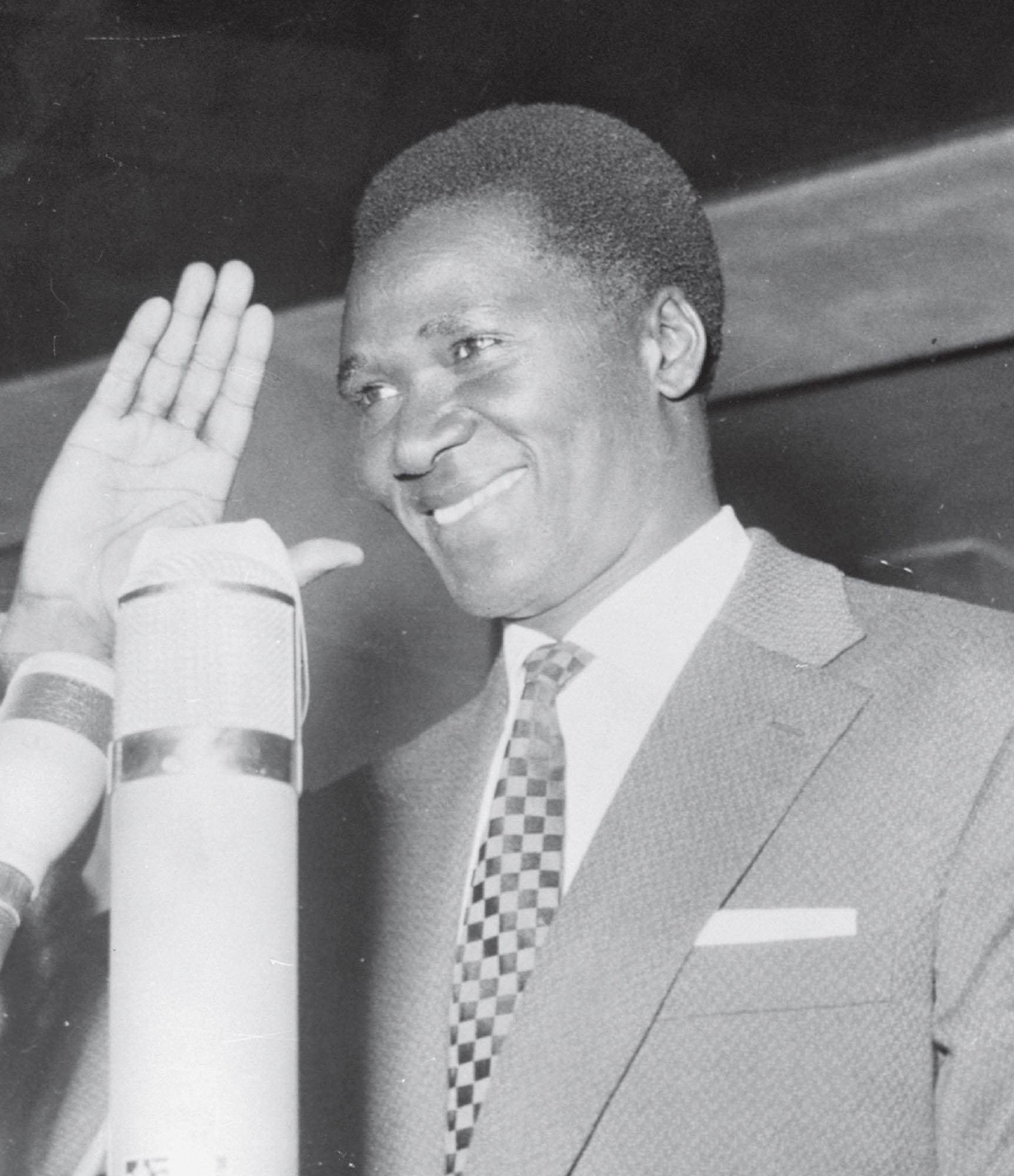 Photo of Guinean political leader Ahmed Sekou Toure with his hand raised in greeting to an unknown individual or group of people.