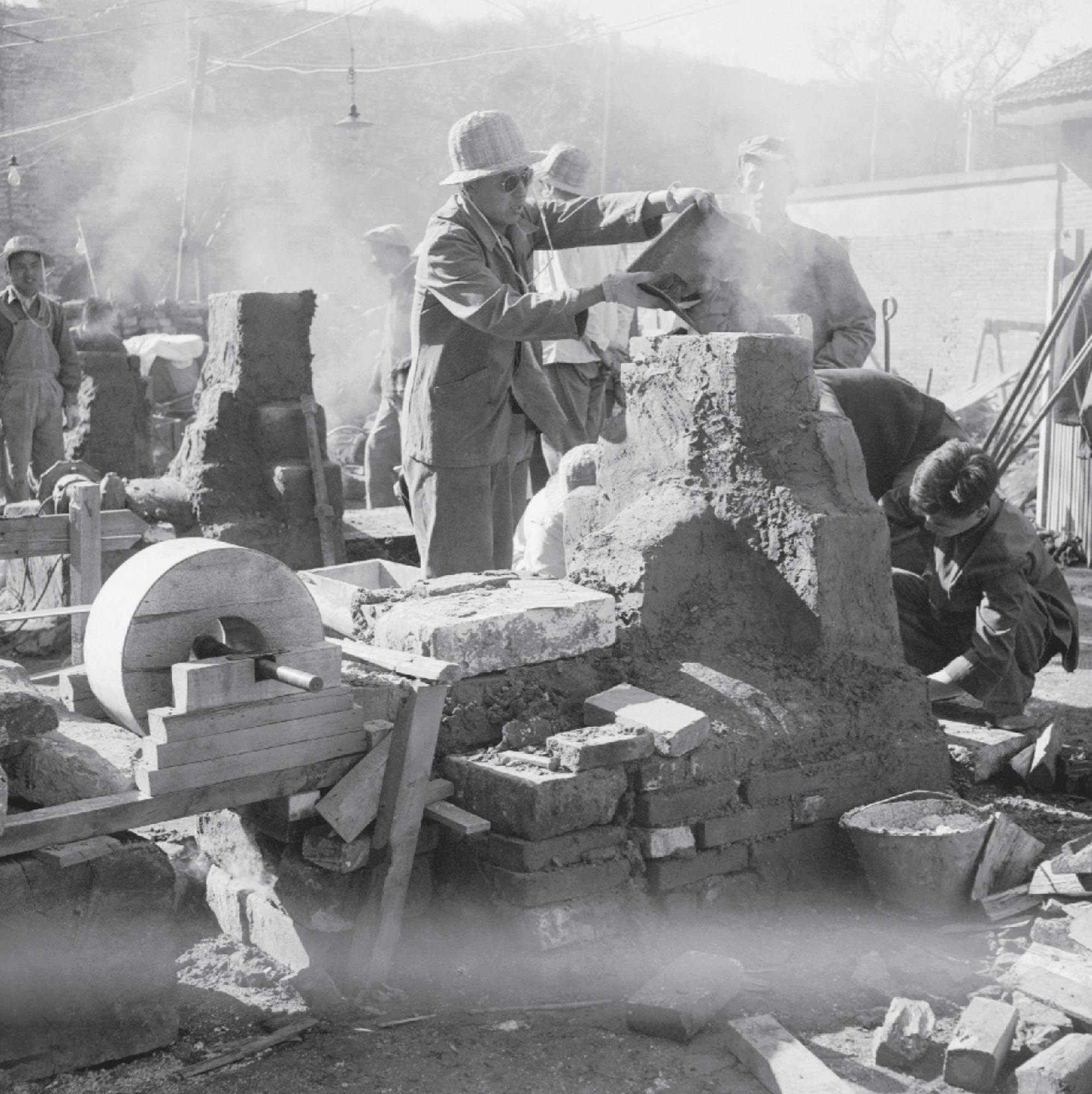 Photo of workers making their own steel using tall, cylindrical barrels.