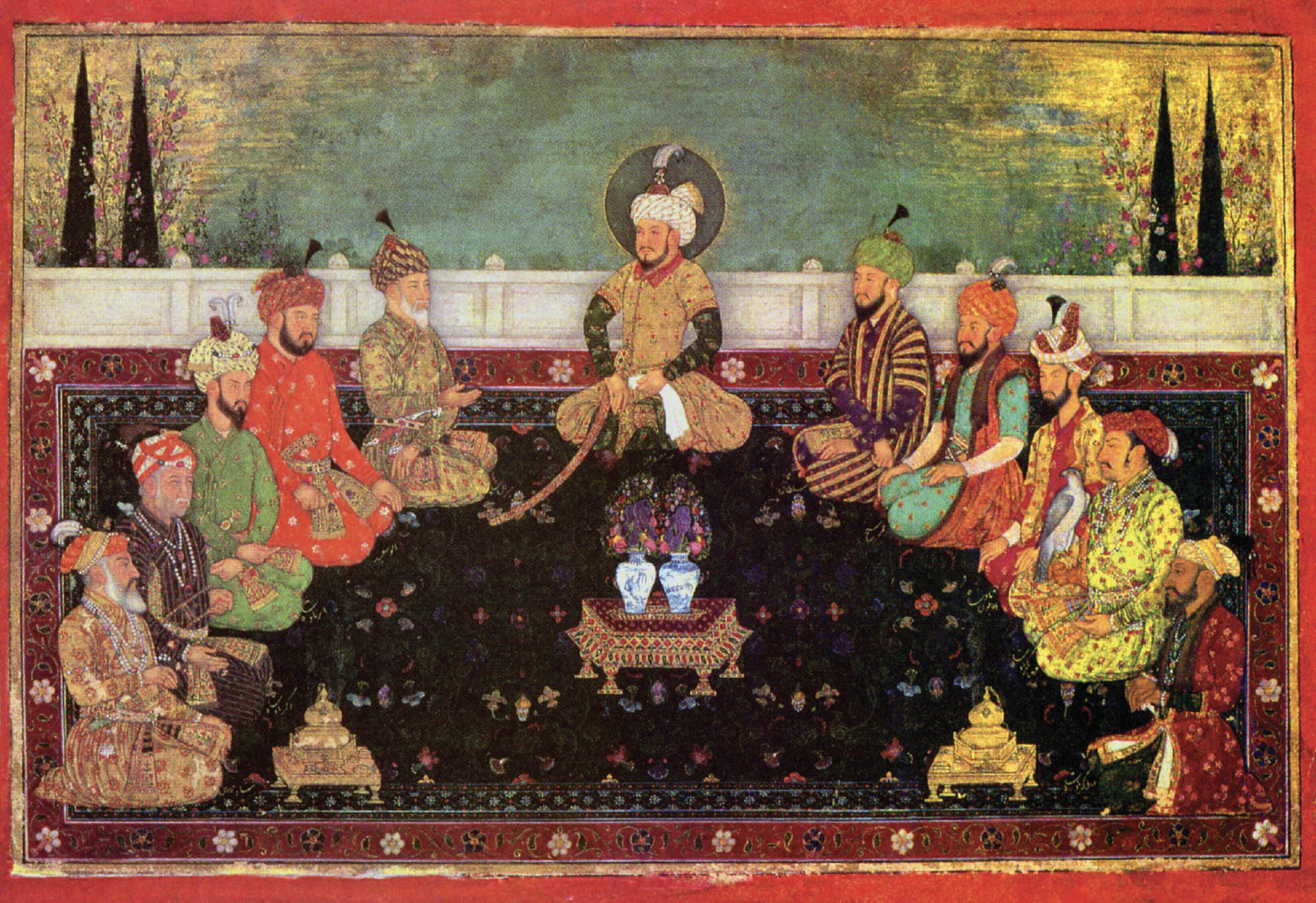 Group of eleven men in colorful clothing sitting cross-legged in a semi-circle. The man in the center has a halo around his head. In the middle of the circle and on the two outer edges there are small tables with vases and hookahs.