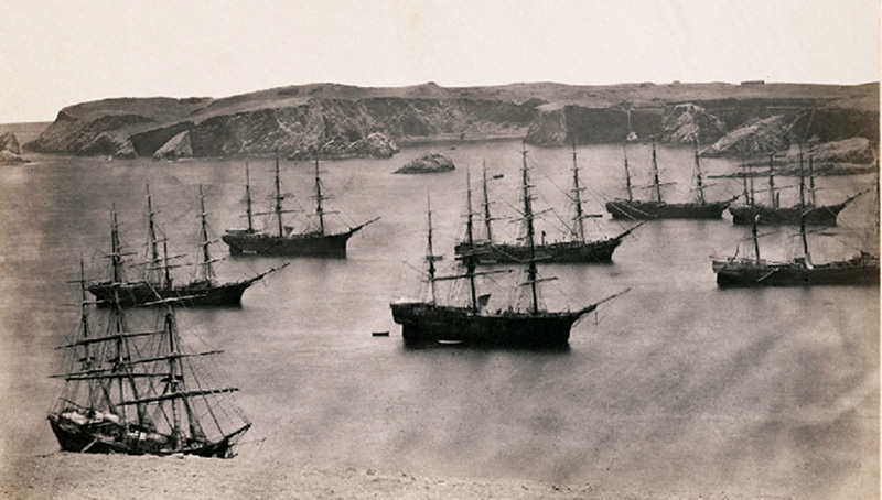 An image from the series, Guano mines in Peru: high-level view of a harbor filled with ships waiting to be loaded.
