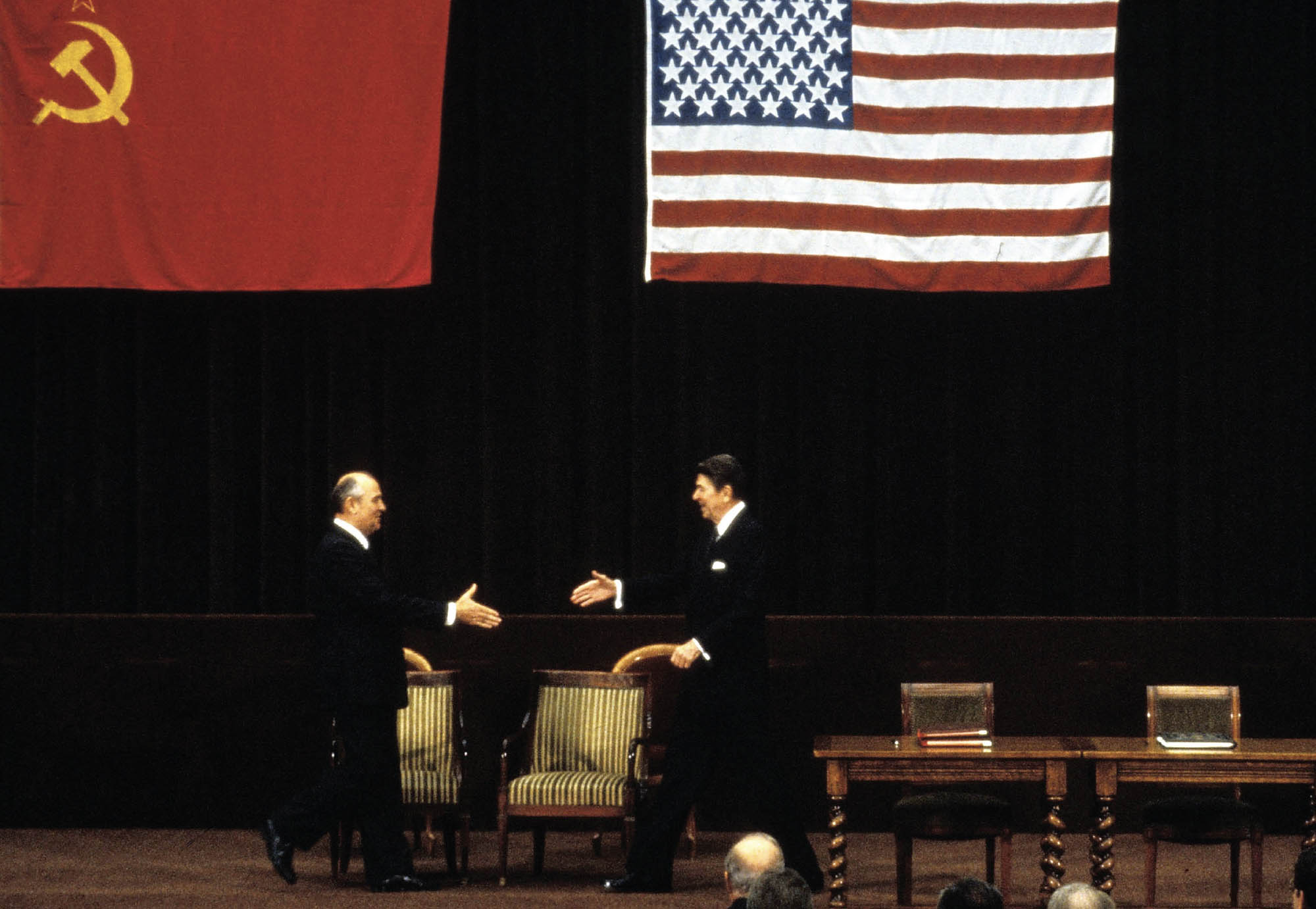 Two world leaders, Reagan and Gorbachev, approaching each other with hands extended.