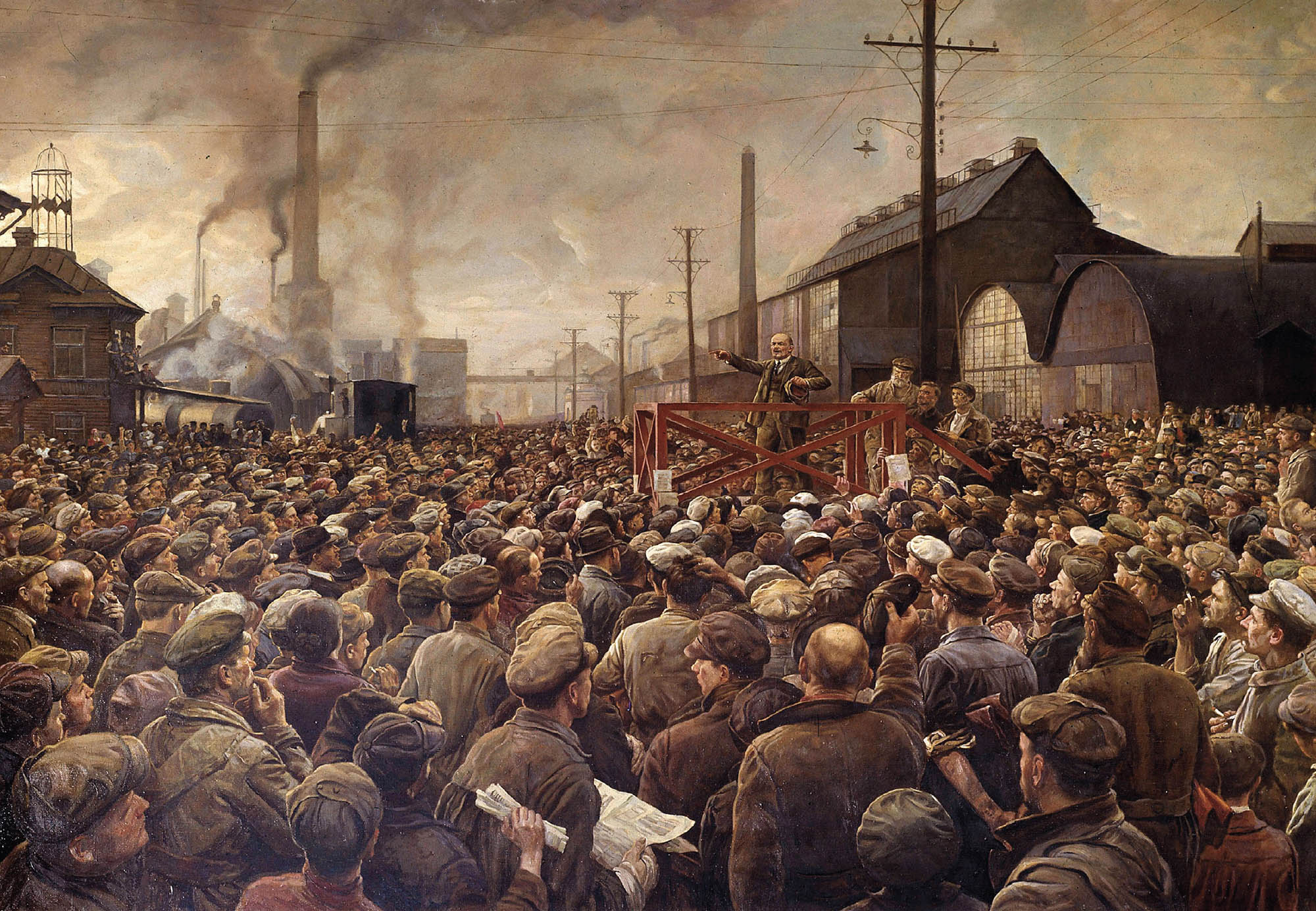 Illustration of a large crowd of people listening to a man in the center give a speech from a platform. Behind them are several industrial buildings.