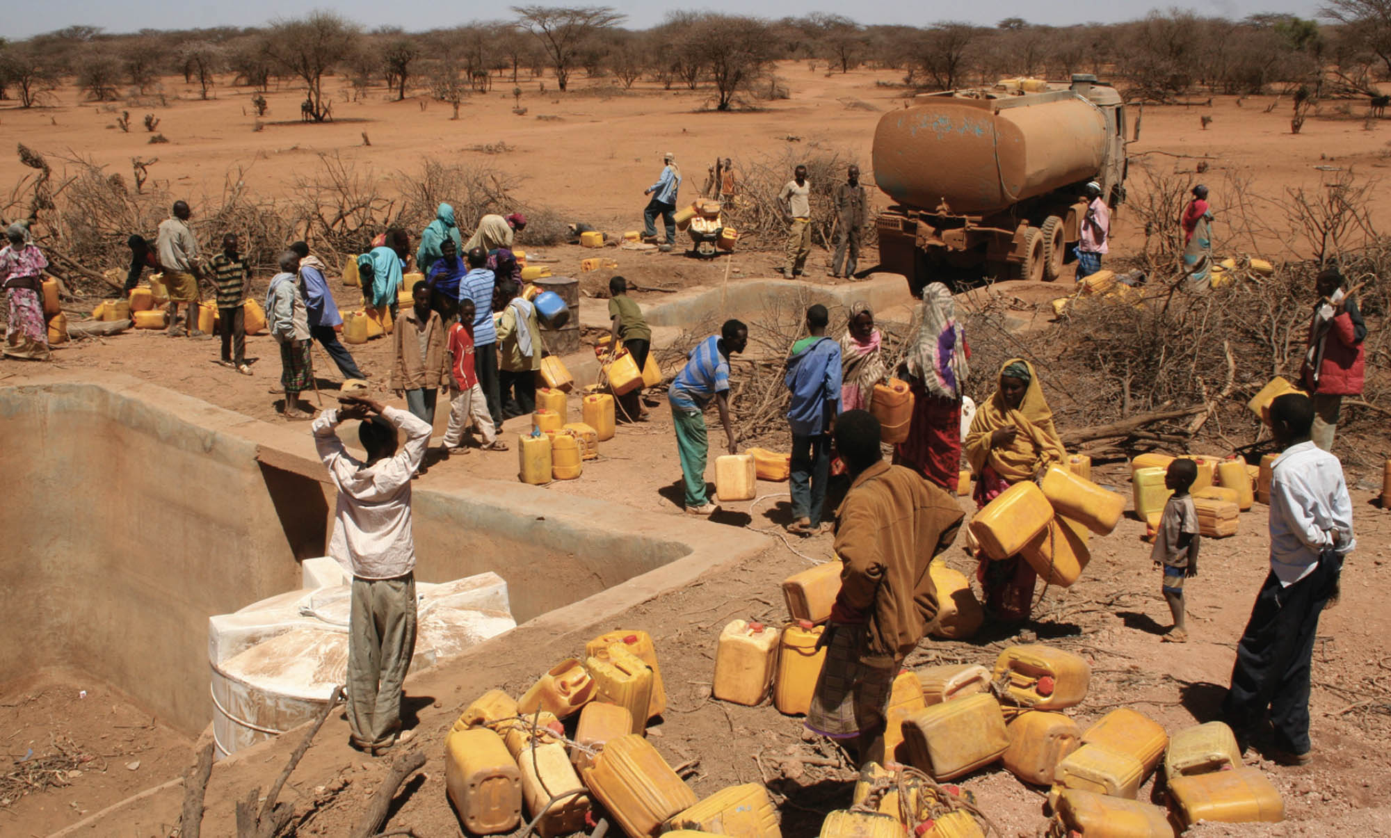 Photo of humanitarian workers distributing large yellow jugs of water to locals in the Horn of Africa during the 2011 drought.