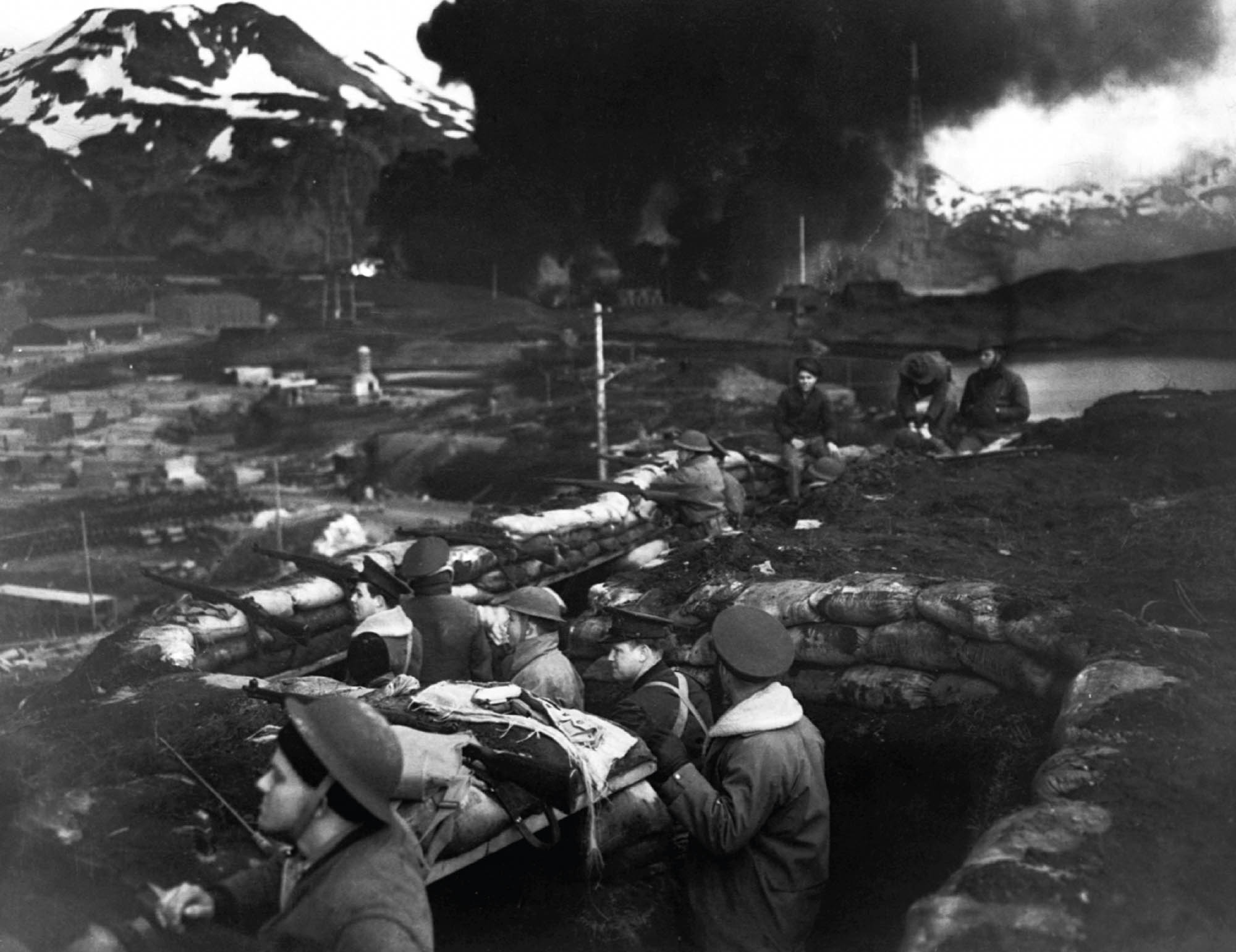 Photo of an Alaskan harbor directly after being bombed by Japanese forces. Large amounts of smoke can be seen billowing into the air.