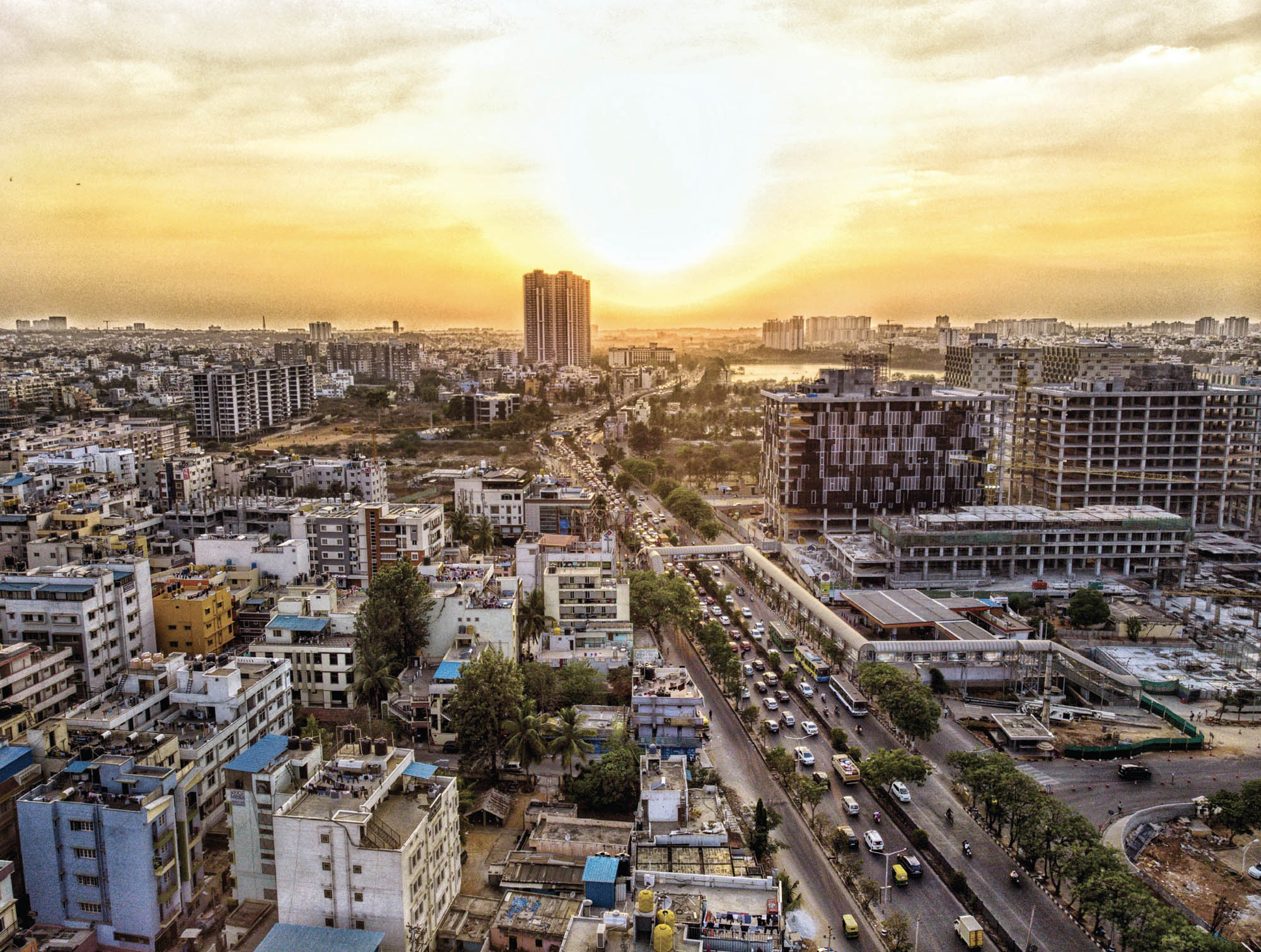 The sun sets over a high angle view of a Bangalore city and street scene.