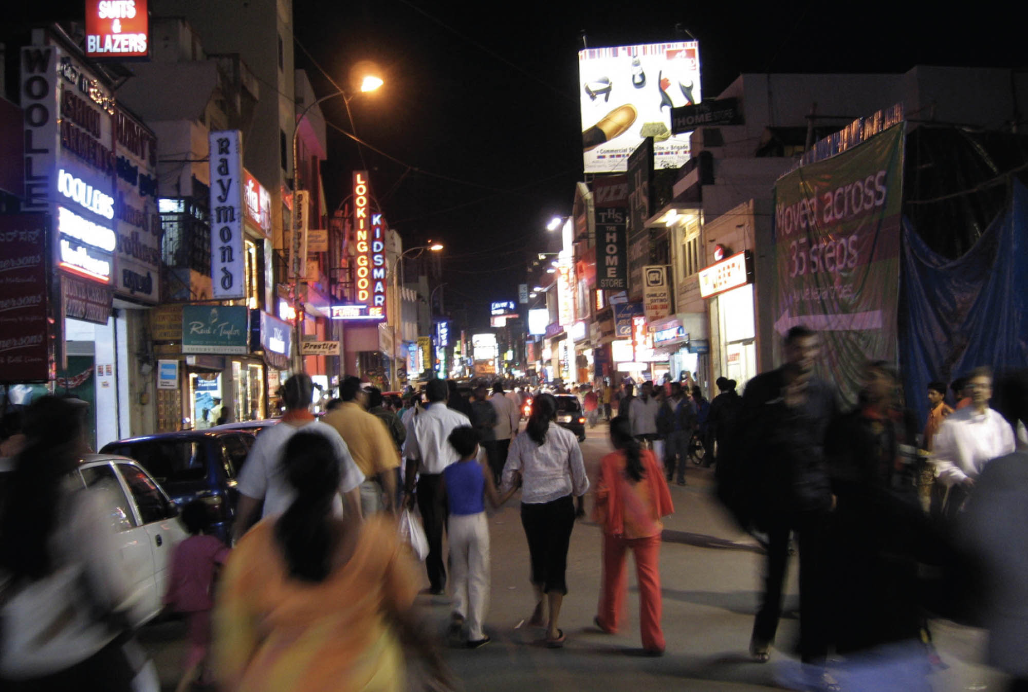 Nightlife scene with a crowd of people and bright signs and lights.