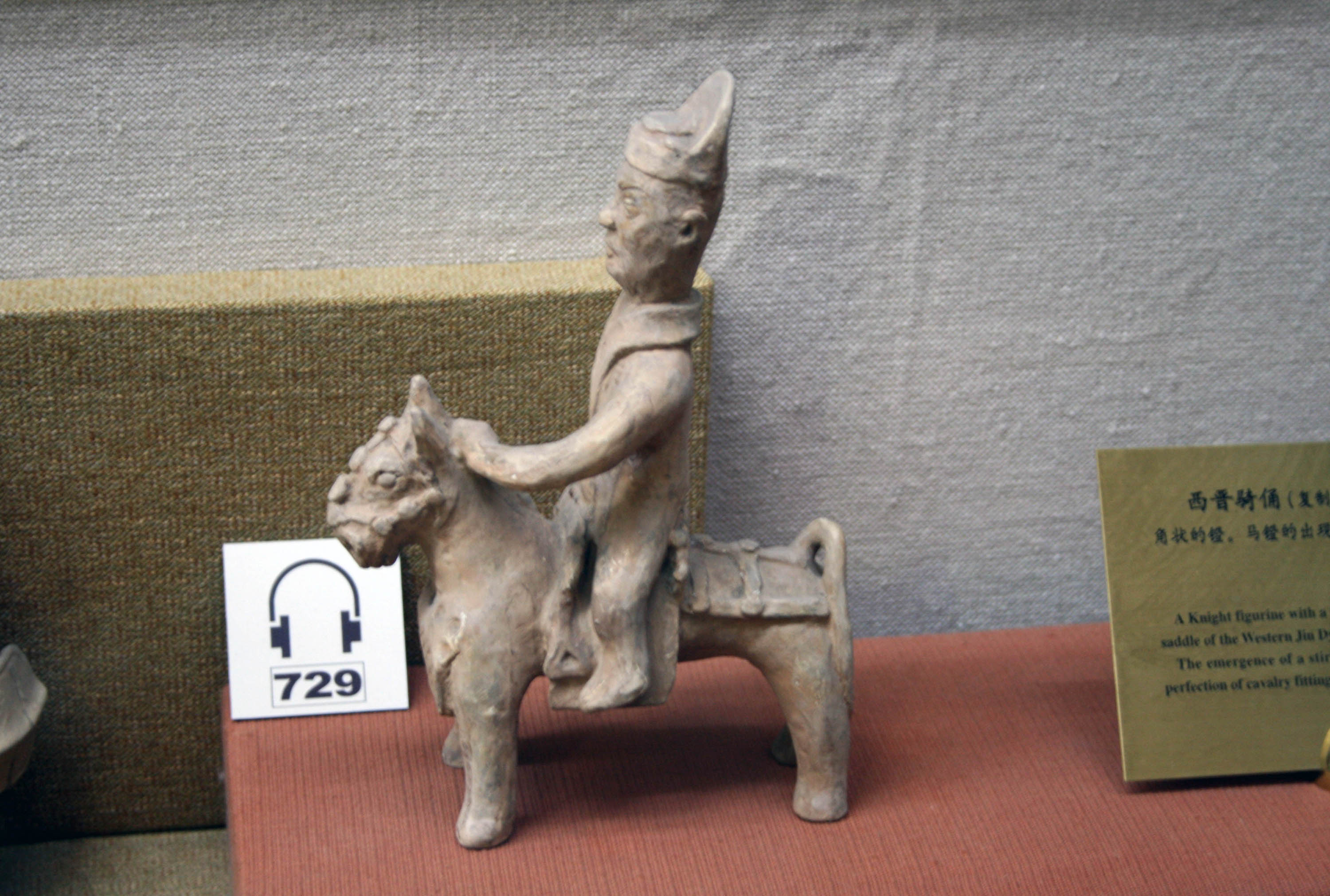 Clay statue of a Chinese rider on horseback from 302 CE, showing an early saddle and visible stirrups near the rider’s legs.
