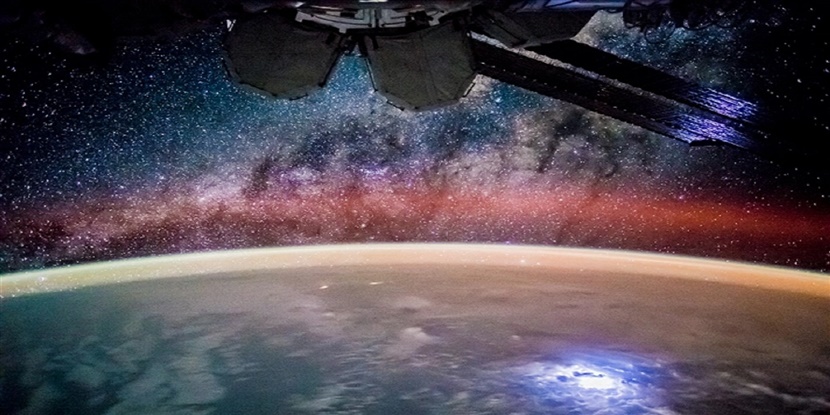 Shot of space looking onto earth and the stars and a satellite.