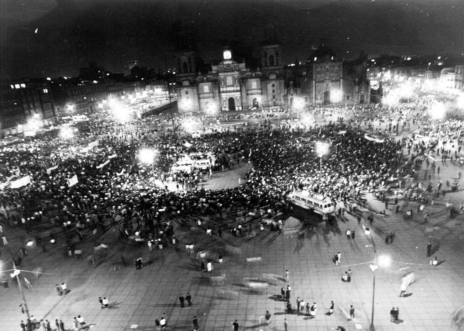 A massive crowd of protesters fill a city square at night in Mexico City.