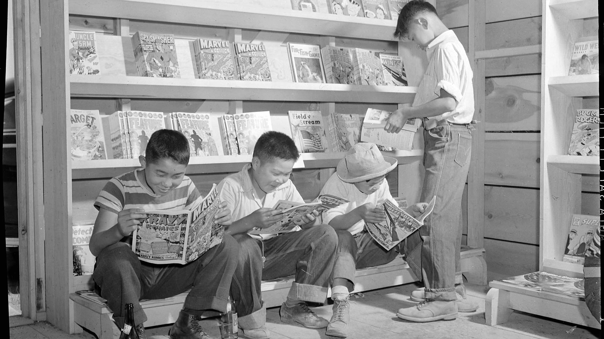 1950s photo of four young boys reading comics at a newsstand.