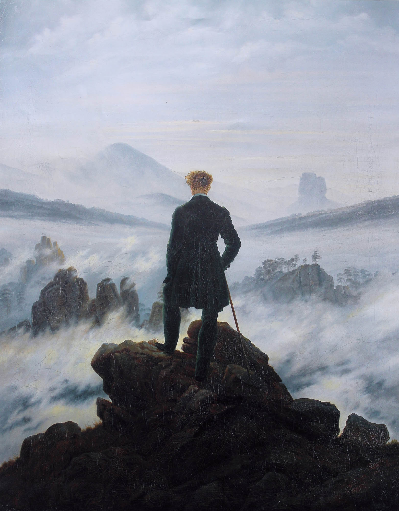 A painting showing a man in a dark overcoat holding a staff and standing on a rugged rock surface overlooking mountains, with his back to the viewers.