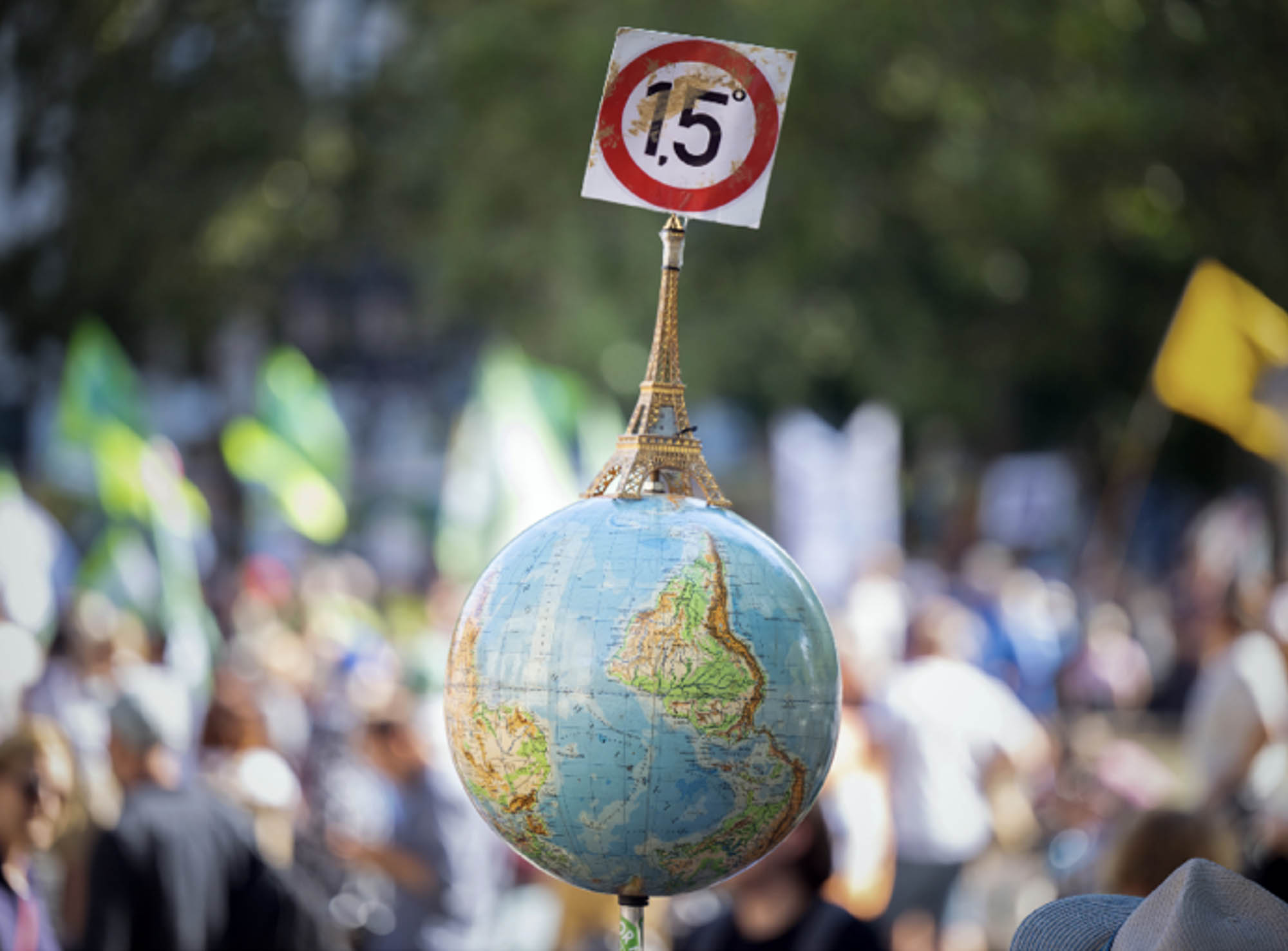 A globe with a miniature Eiffel Tower and the 1.5-degree target of the Paris climate agreement is carried by a man at a demonstration.