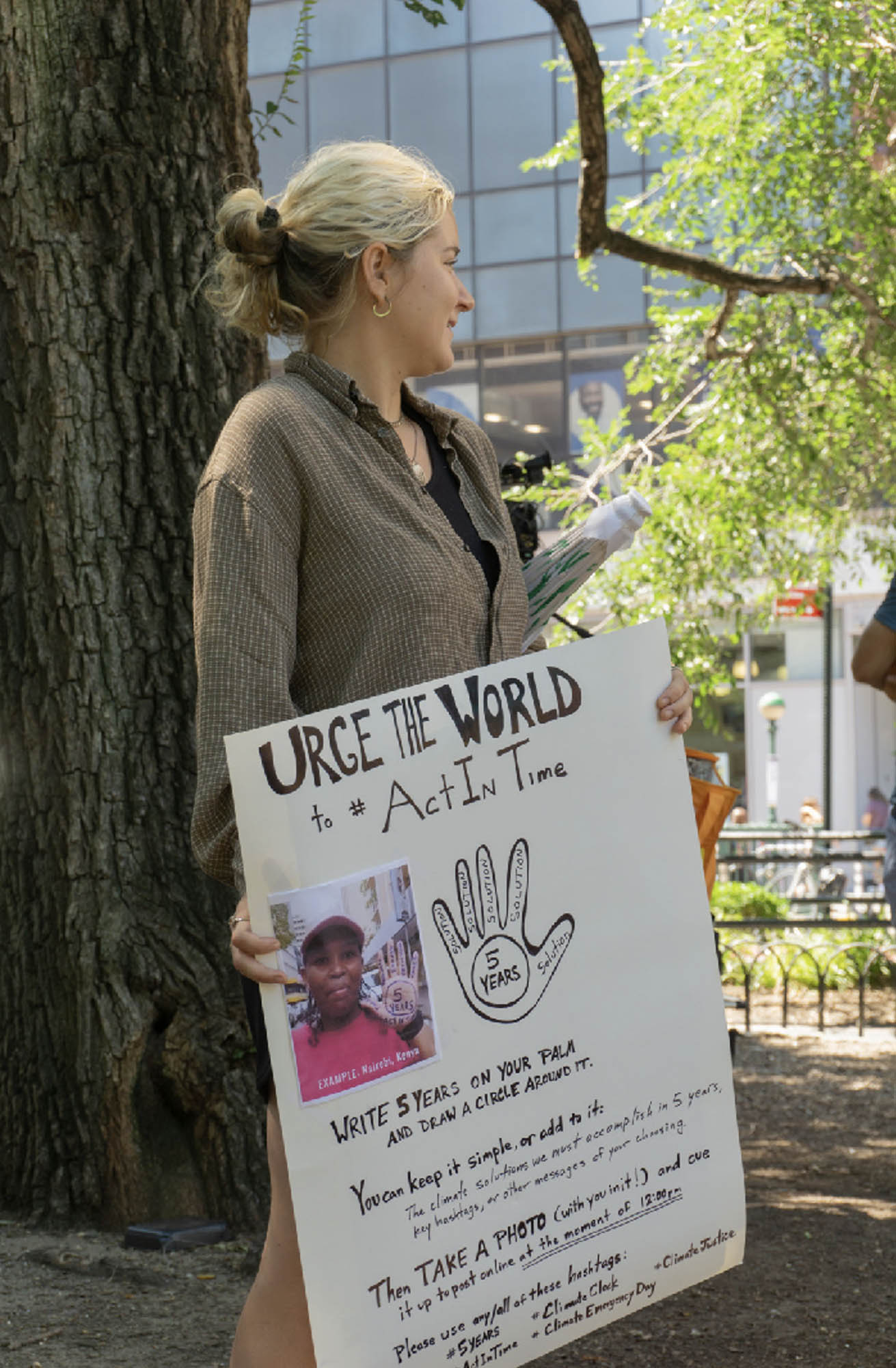 A protestor holds a poster as that urges the world to “Act in Time,” and outlines actions that individuals might take for the five-year deadline to take drastic actions to cut fossil fuel emissions.