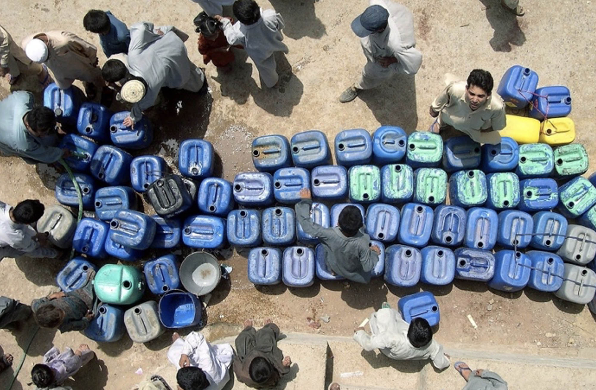 A rooftop view shows a long queue of jerrycans as people wait for their turn to fill them with potable water in Karachi, 17 June 2003.