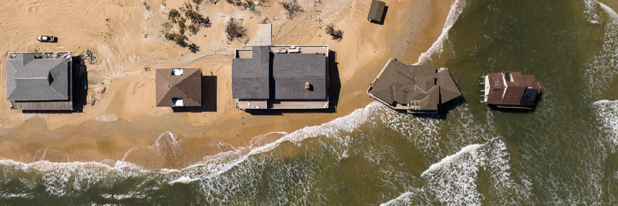 Overview drove shot of waterfront homes inundated by rising sea and waves.