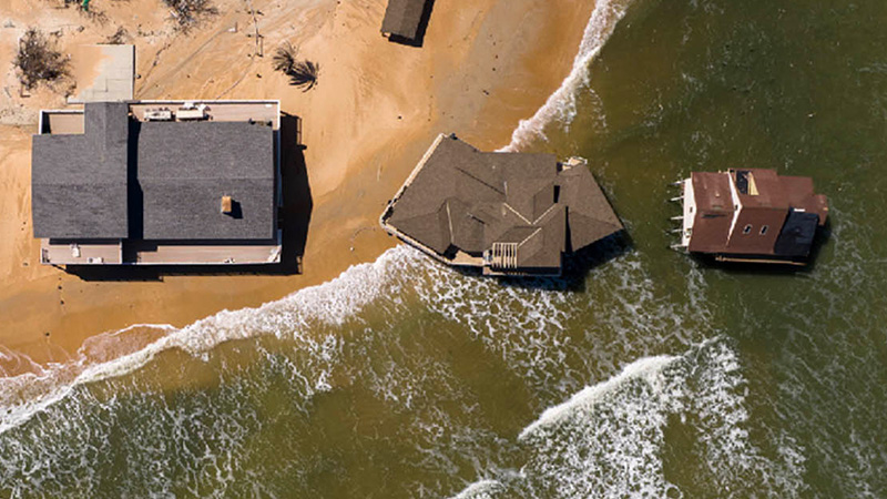 Overview drove shot of waterfront homes inundated by rising sea and waves.