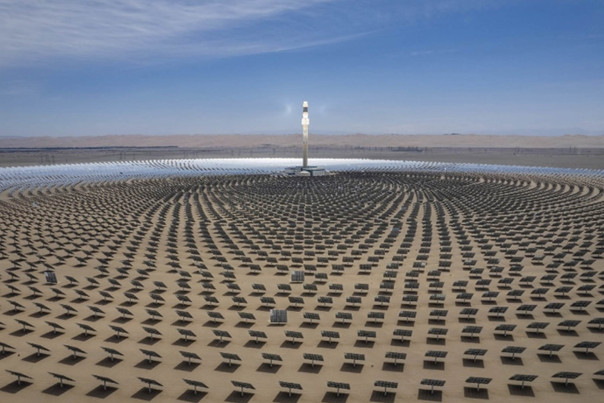 A part view of a solar thermal power station with mirror reflectors concentrating lightbeams onto a central tower.