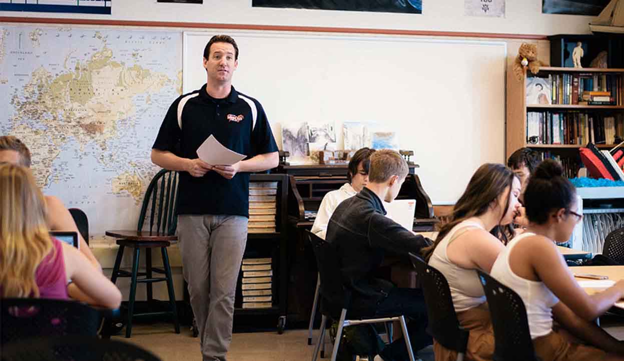 teacher holding paper in a classroom