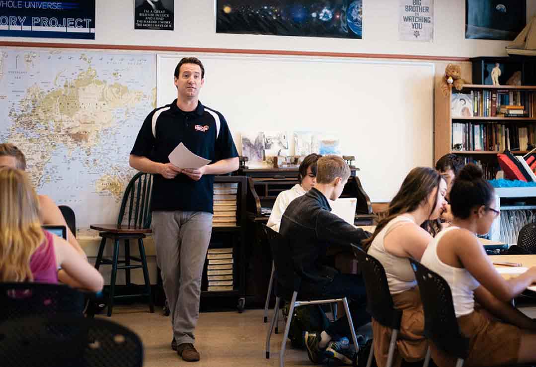 teacher holding paper in a classroom