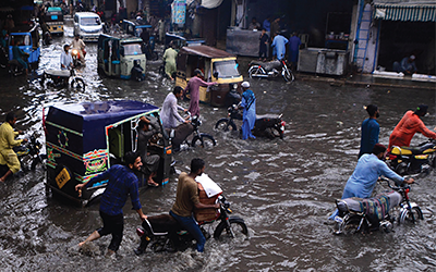 People hardly drive their vehicles through flooded street following heavy monsoon rains which submerged low lying areas causing property damages to houses in Hyderabad, southern Sindh province, Pakistan, on July 24 2022.