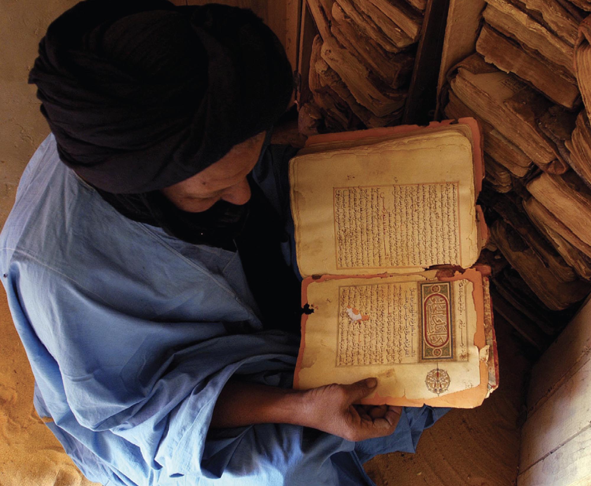 Photograph of a man holding an ancient manuscript.