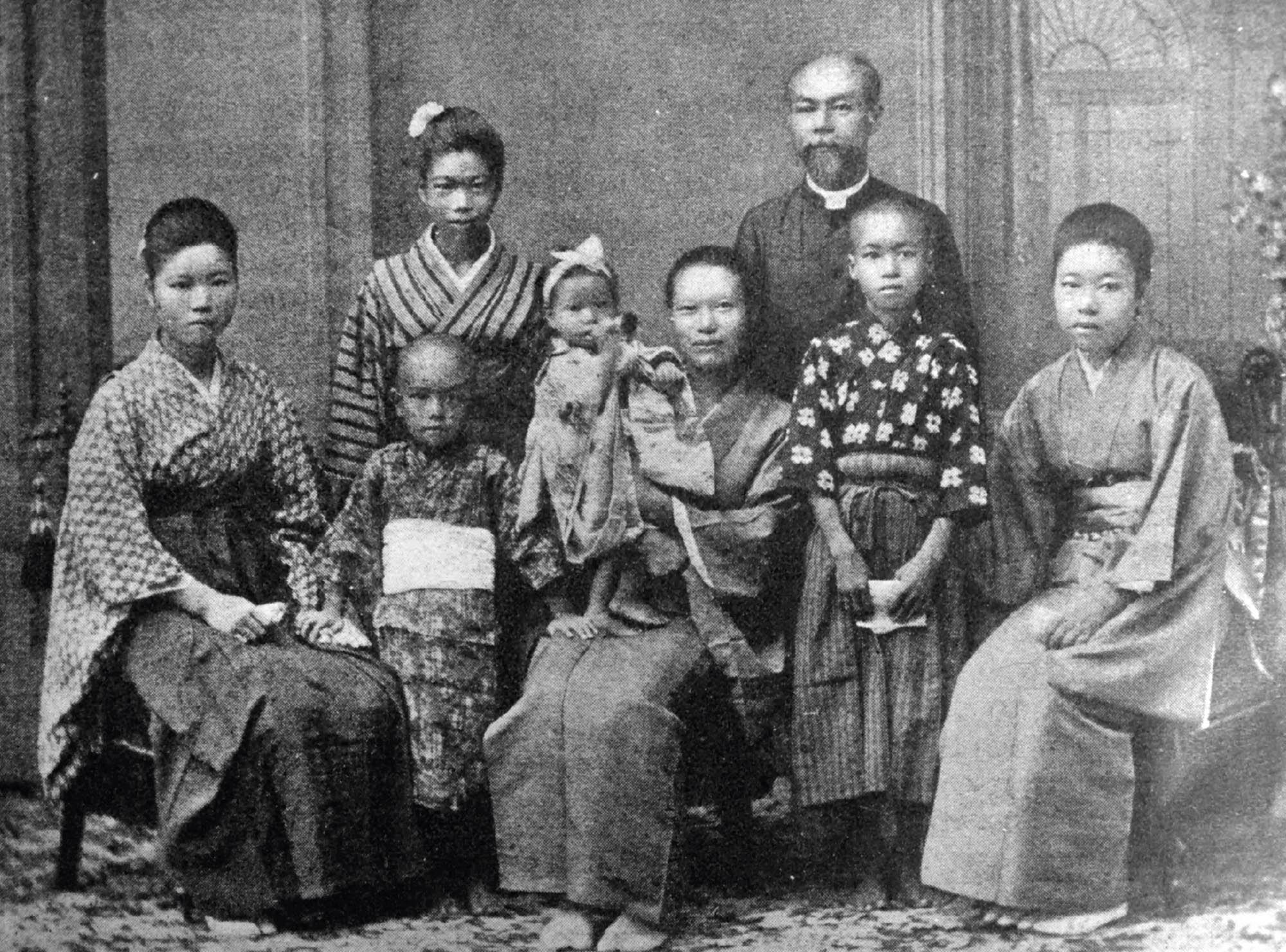 A large Japanese family, dressed in traditional clothing, pose for a group photograph.