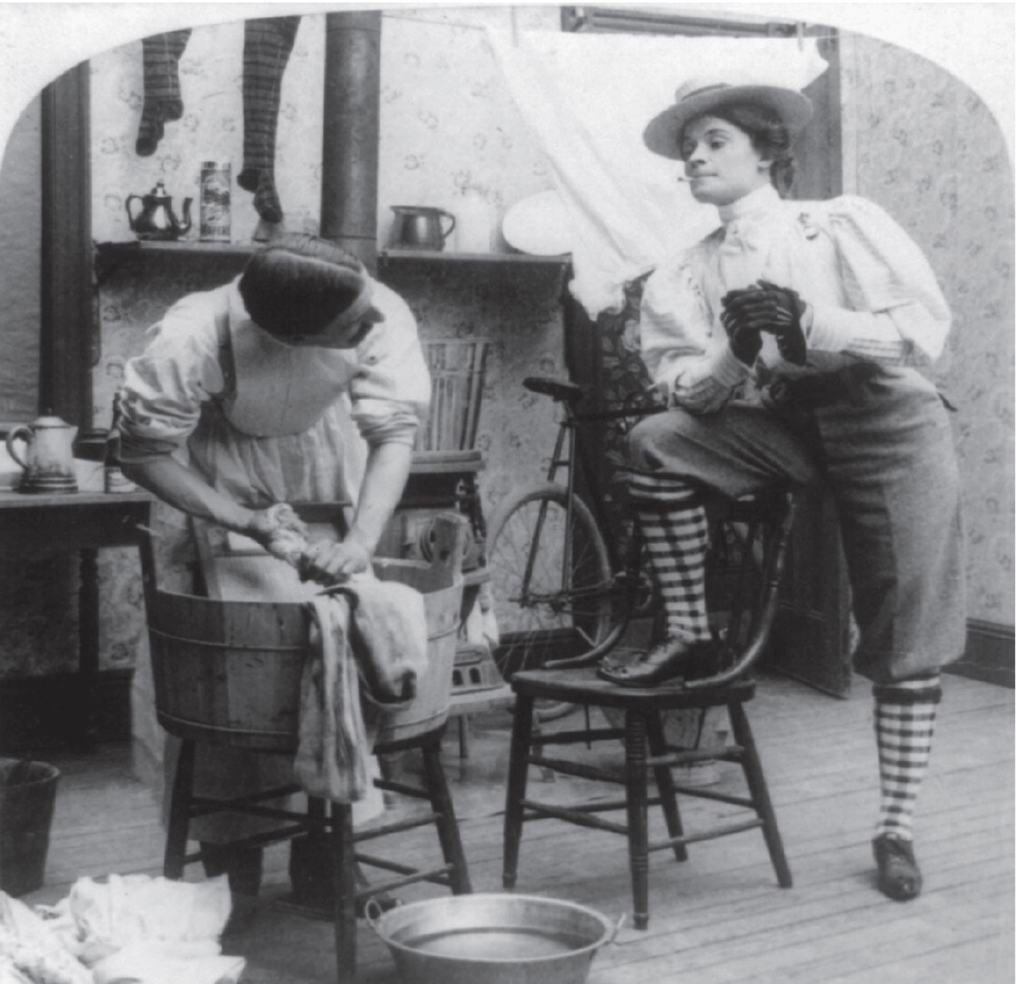 Satirical photo of a woman dressed in man’s clothing observing her husband doing chores.
