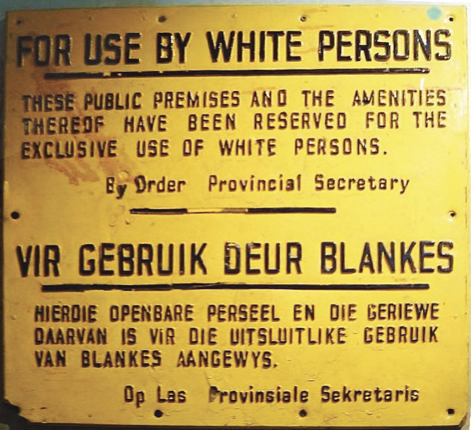 Photo of a yellow sign written in English and Afrikaans that states “For use by white persons”.