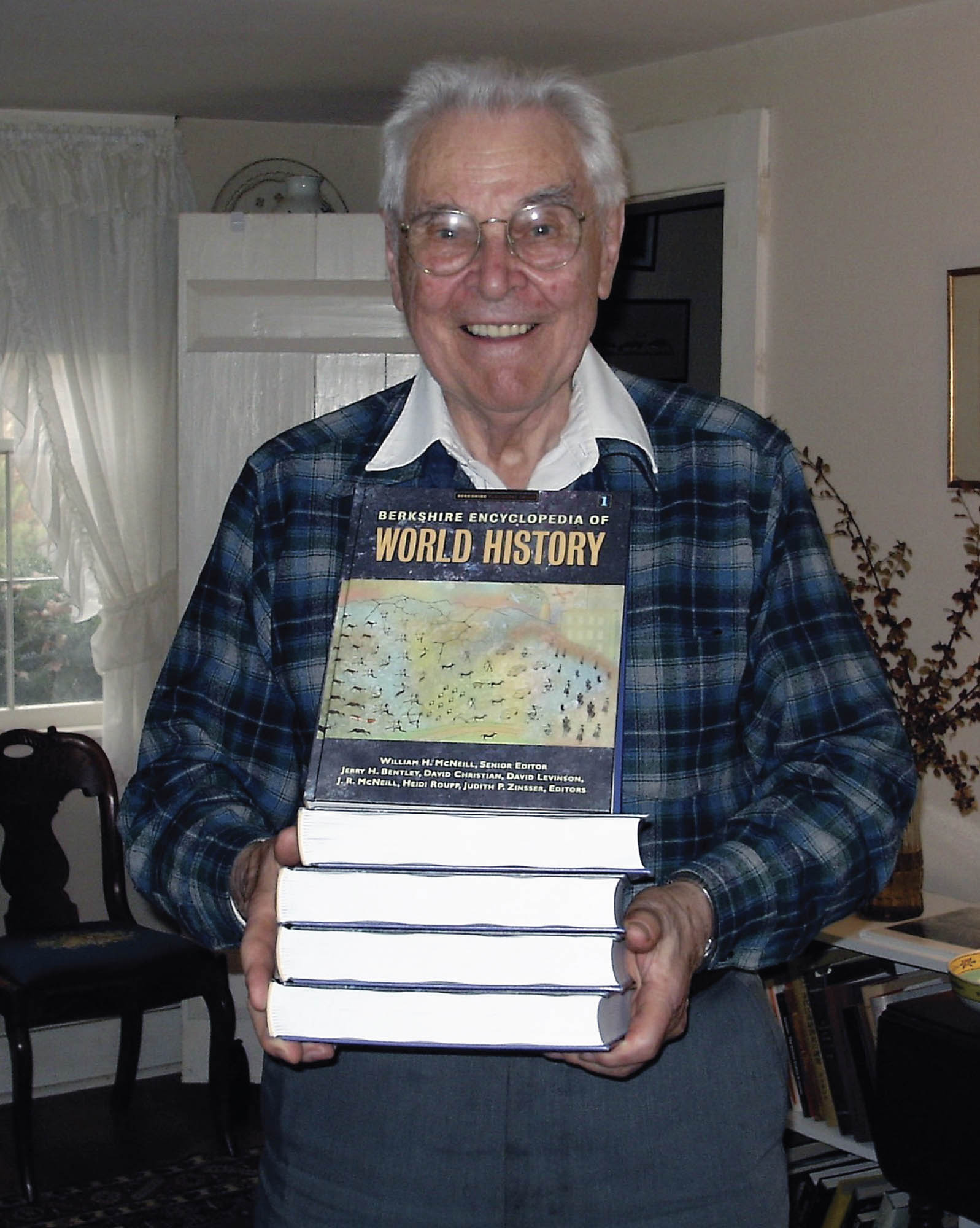 Photo of historian William McNeil holding several copies of The Berkshire Encyclopedia of World History.