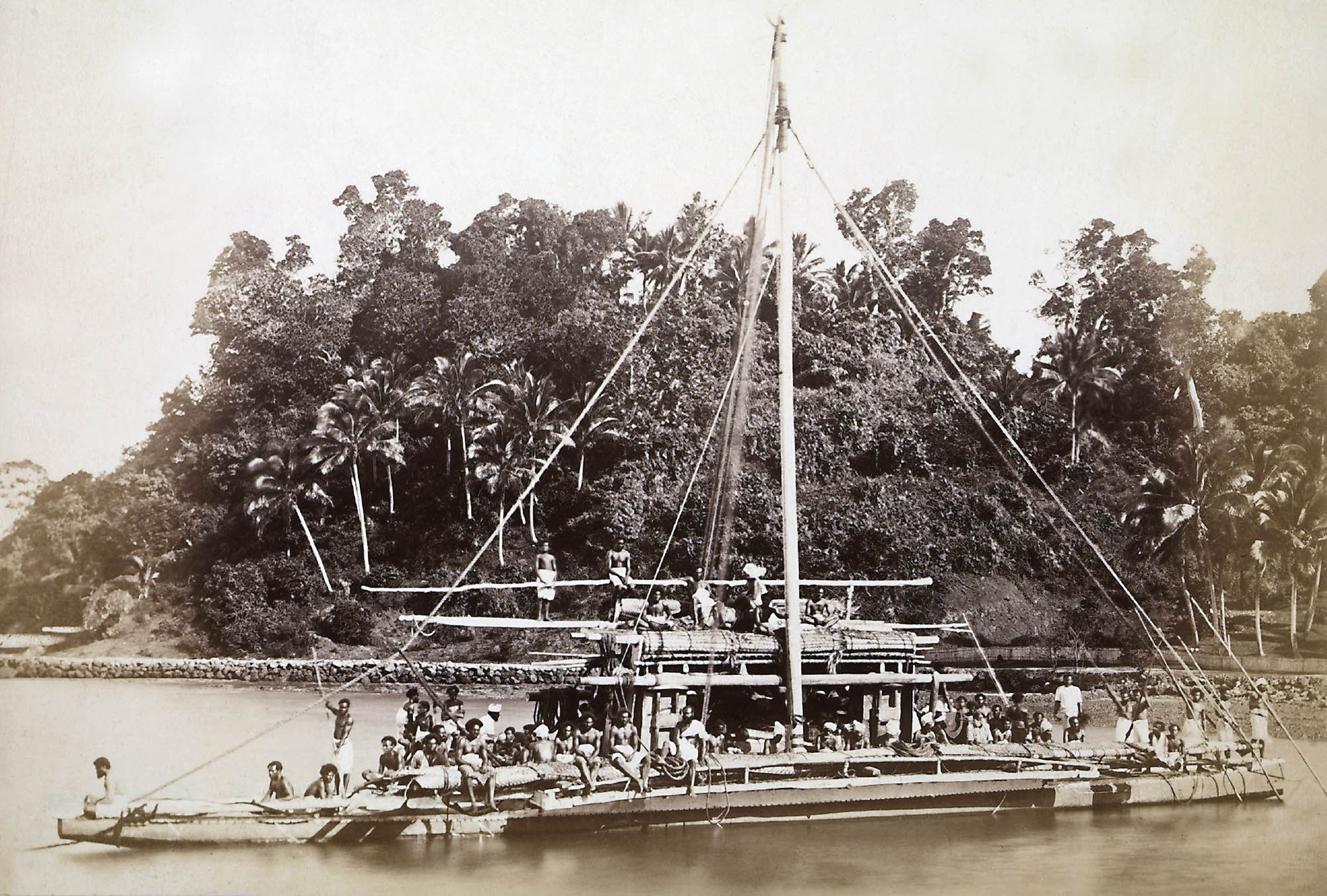 Photo of a large ship made entirely from planks of wood. Groups of workers line the boat’s hull, some with long, wooden poles in their hands.