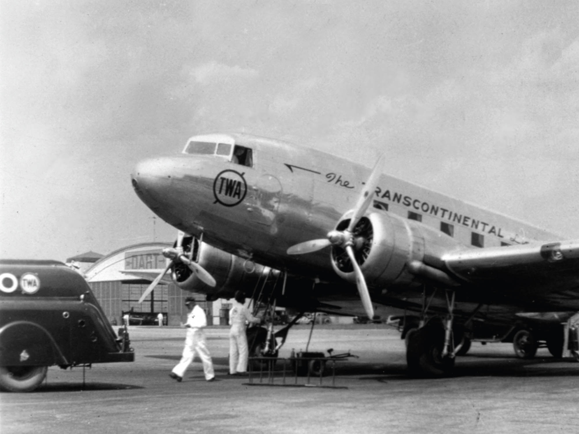 An early commercial airplane getting fuel and groundcrew service in preparation for takeoff.