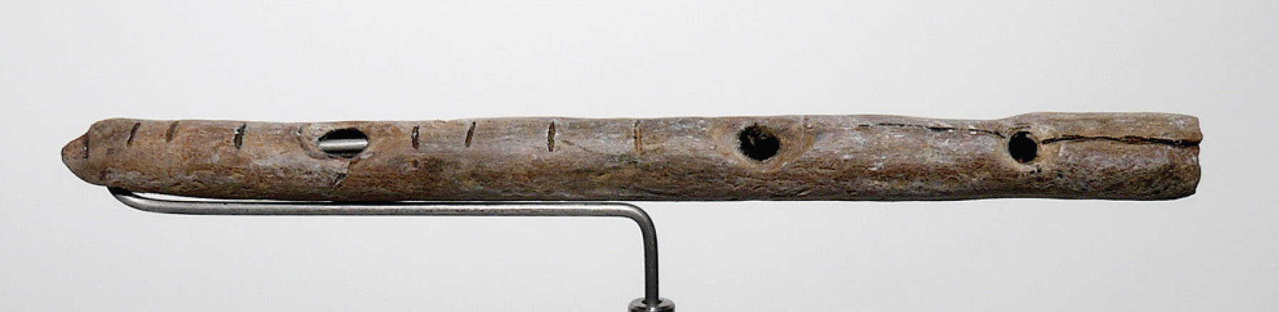Bone flute with notches and three holes for creating different pitches
