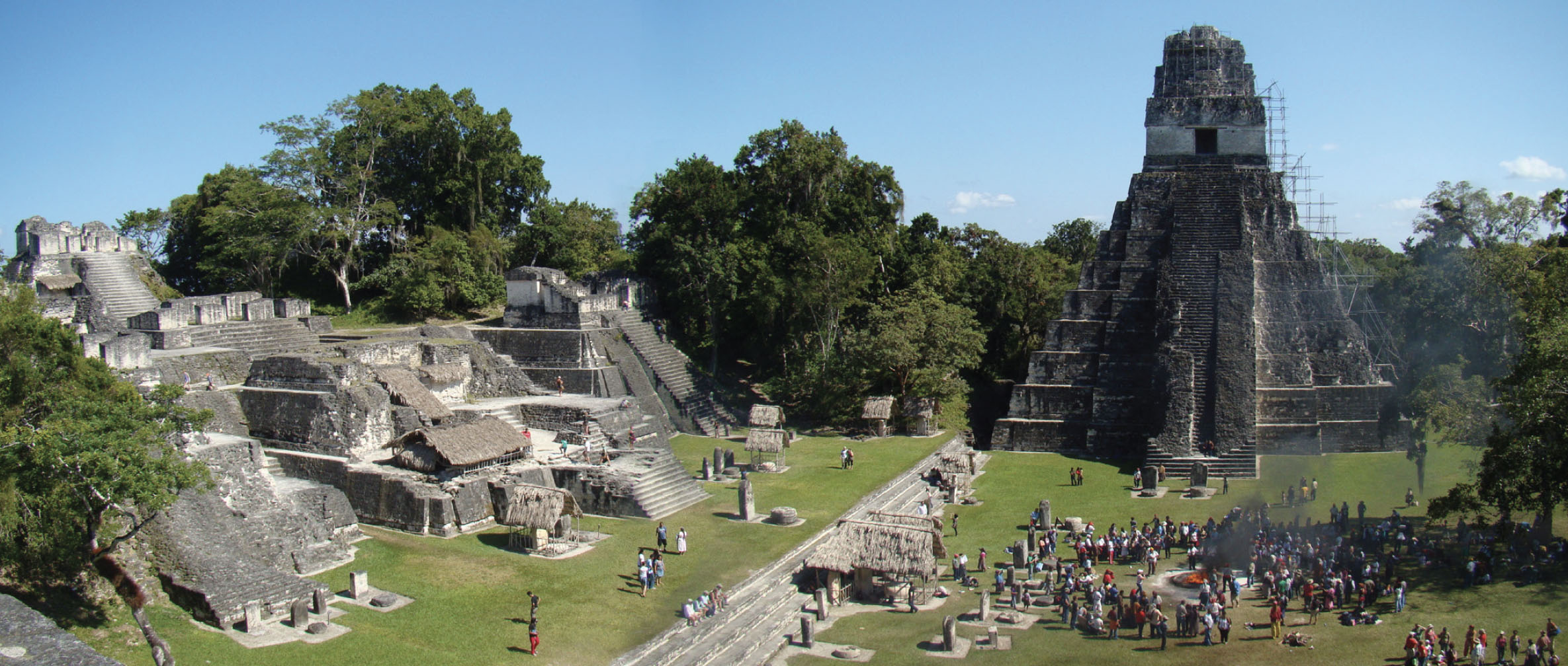 Modern day image of many people visiting an ancient ruins site that features a large, tower-like structure and several smaller brick structures.