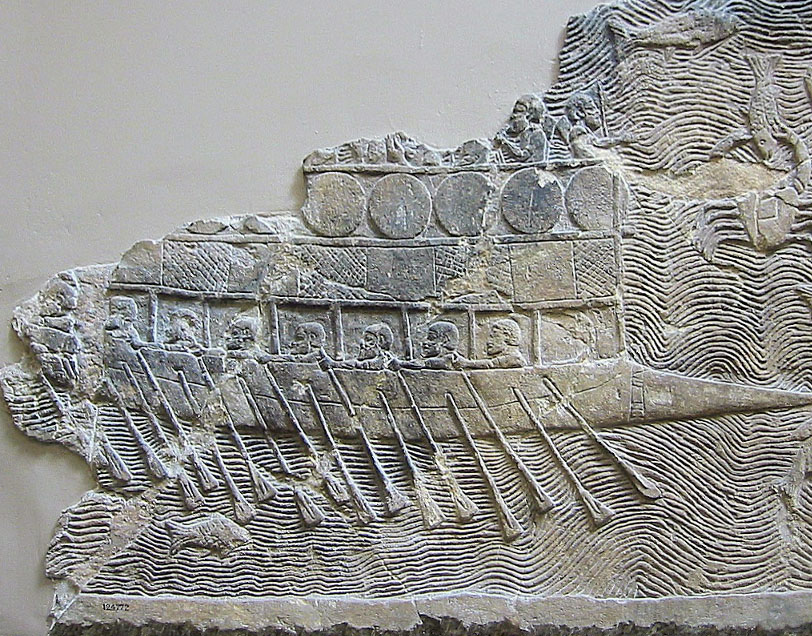 Fragment of a detailed rock carving depicting a ship on the sea, with men rowing the ship using oars. The sea is shown with wavy lines, and there is a fish swimming beneath the boat.