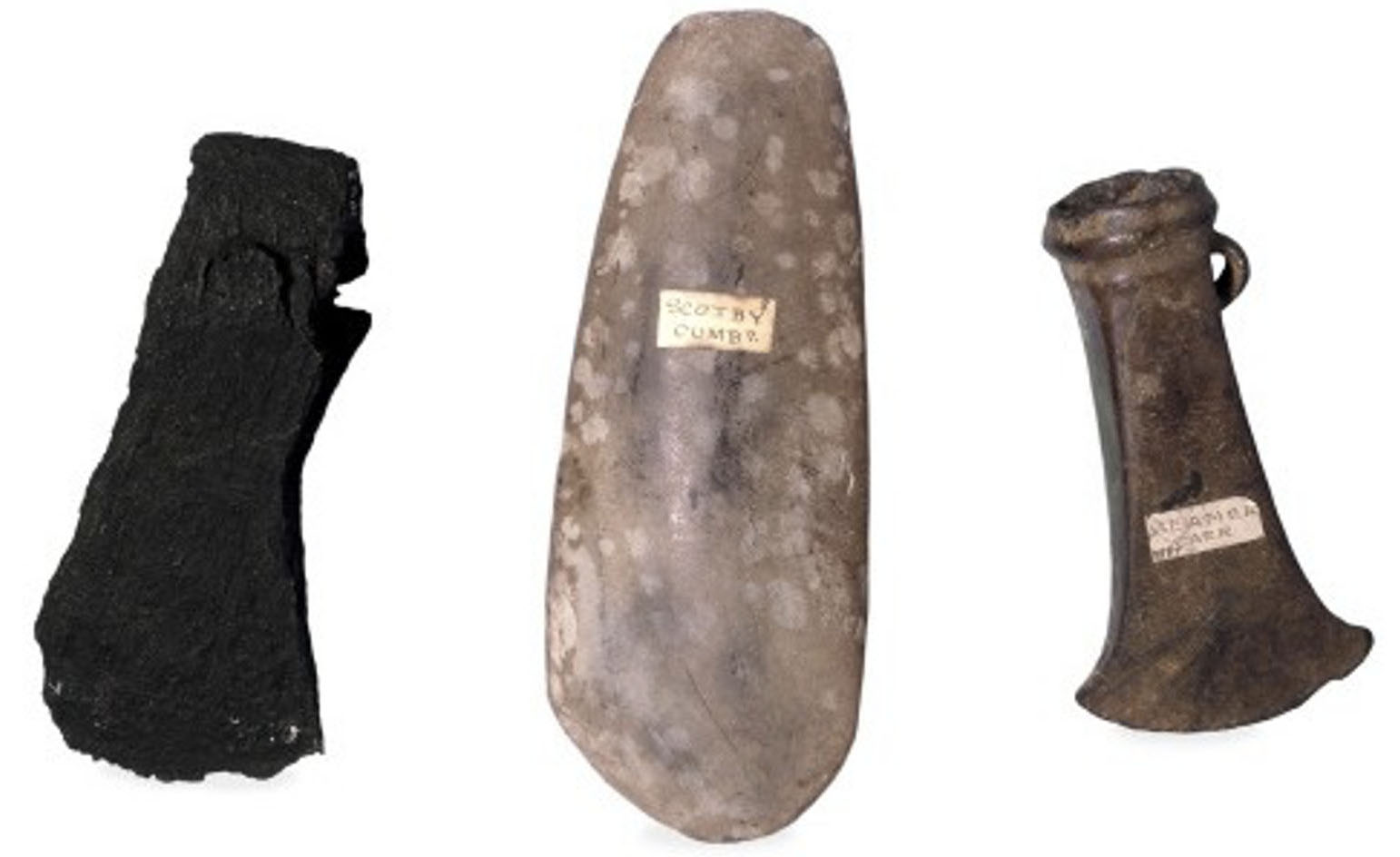 Photograph shows a comparison of axes from three ages; iron axe is blackened and broken down around the edges
