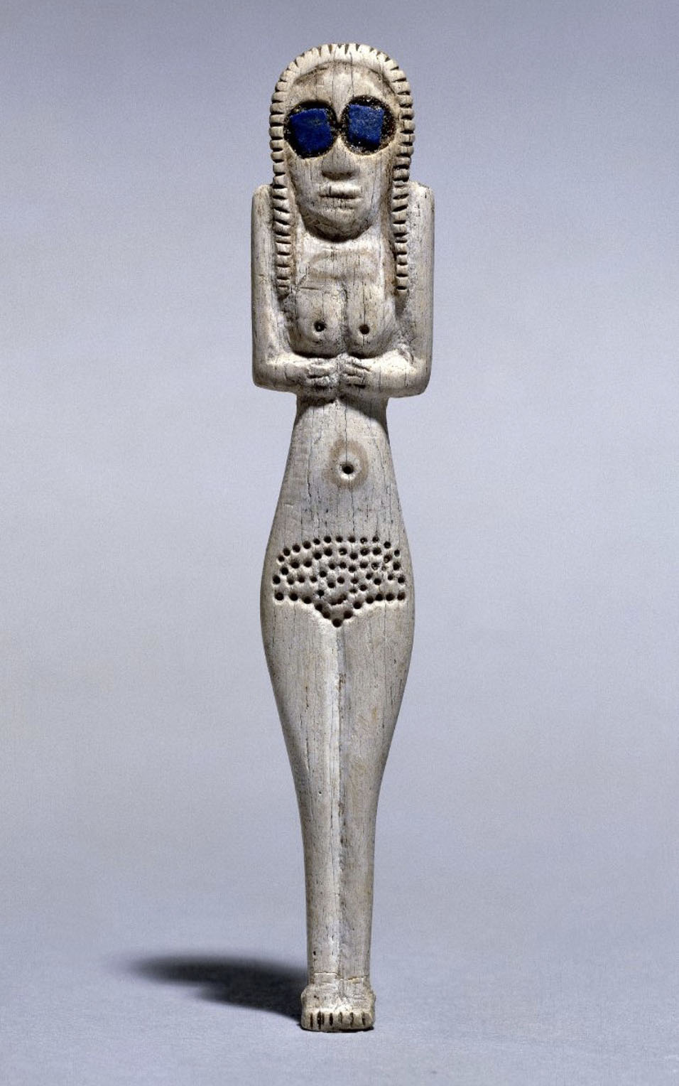 A figure of a woman carved out of bone, with large blue stones for eyes
