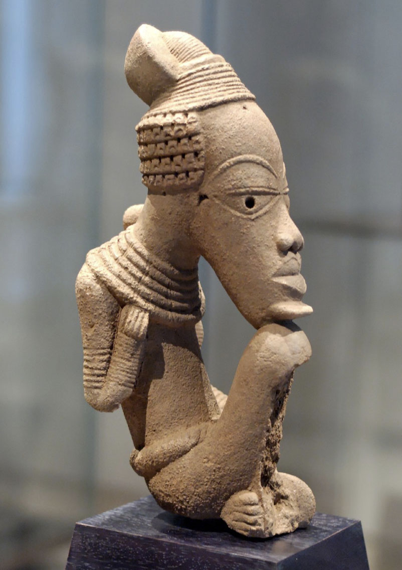 Sculpture of a figure with an elongated face in a seated position