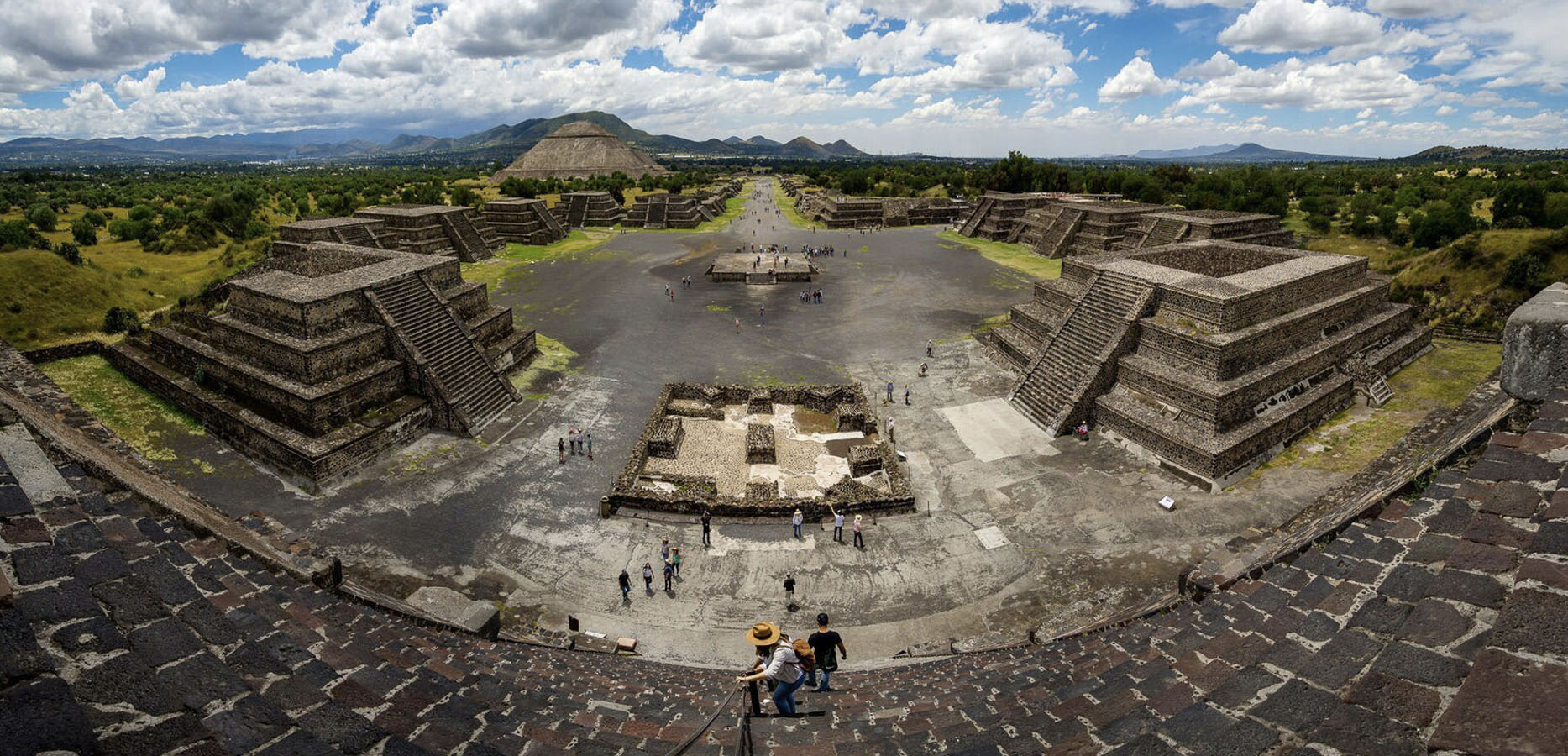 Birds-eye view of what remains of Teotihuacan. There are several large, leveled structures featuring staircases, and one larger pyramid-shaped structure