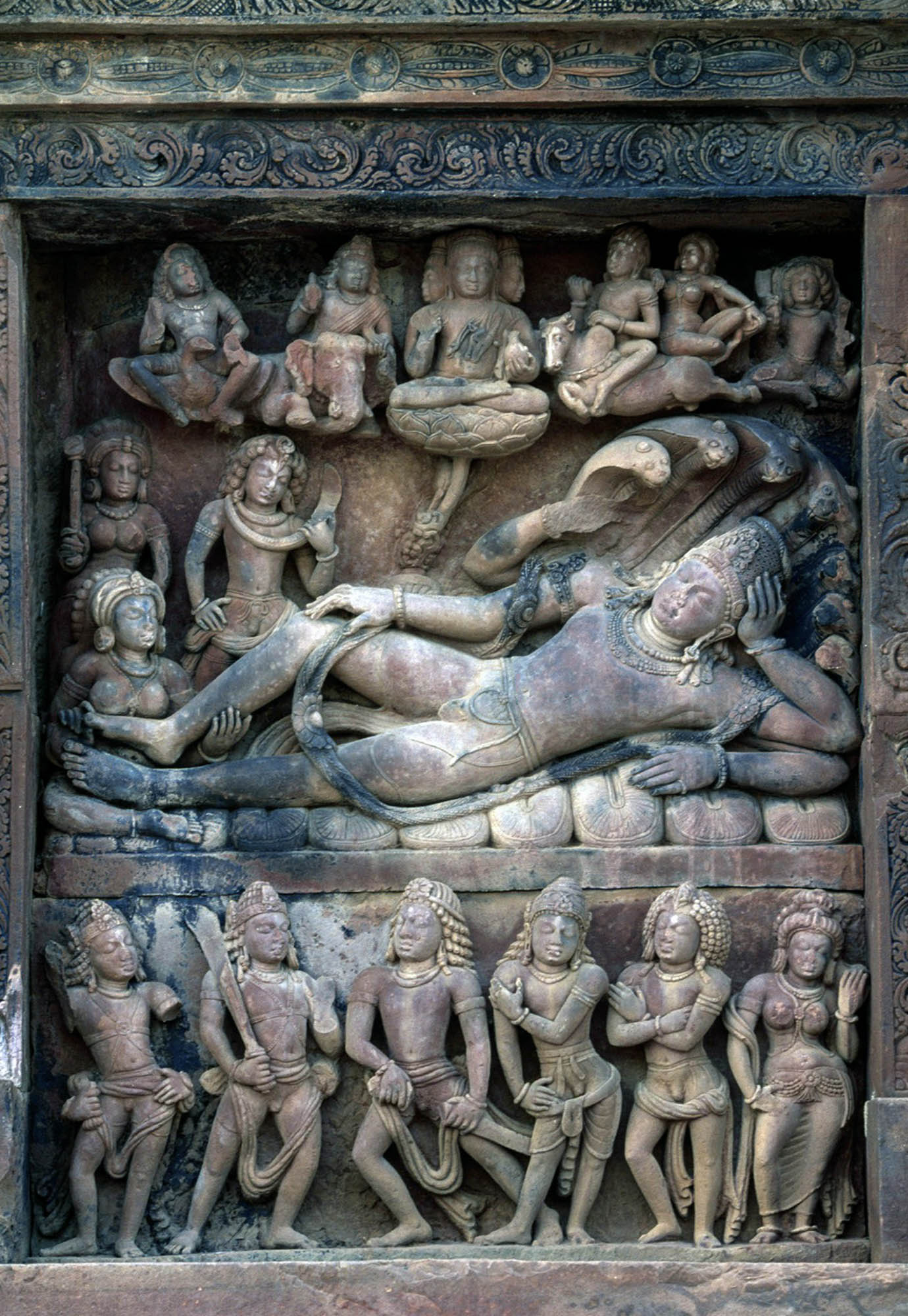 Detail of a stone and masonry brick temple with a carved panel with figures within it.