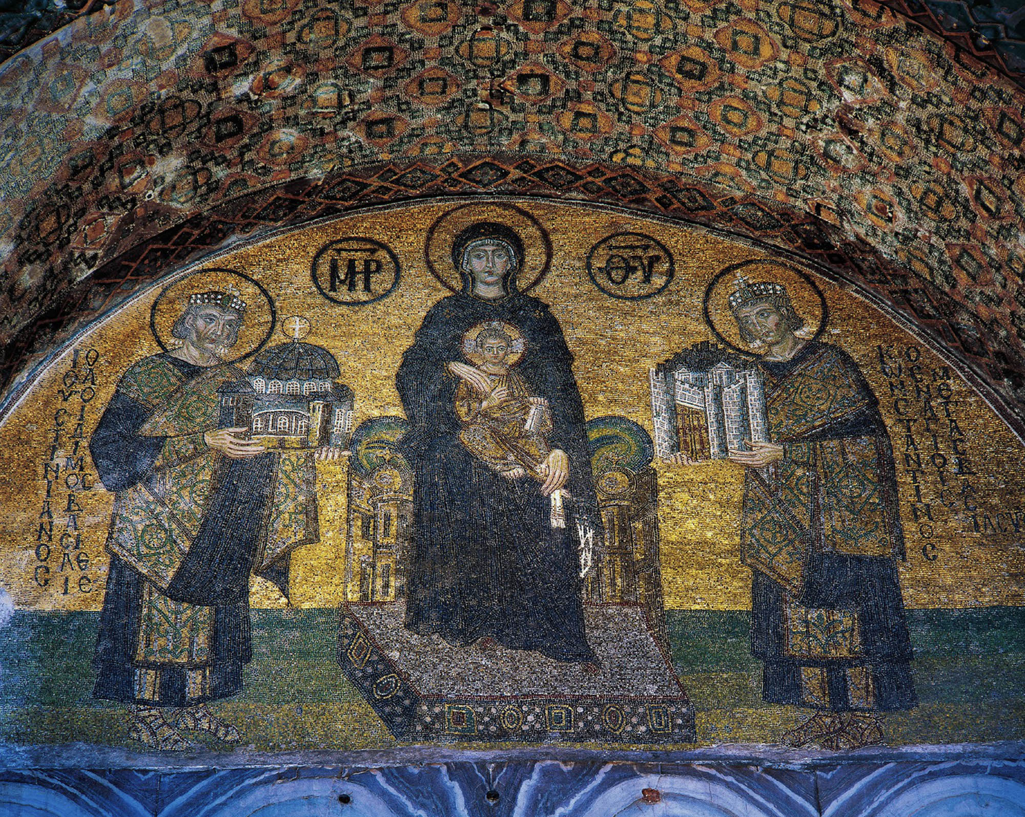A mosaic in an archway with a golden background and Virgin Mary and the Christ child on her lap in the center between two emperors.