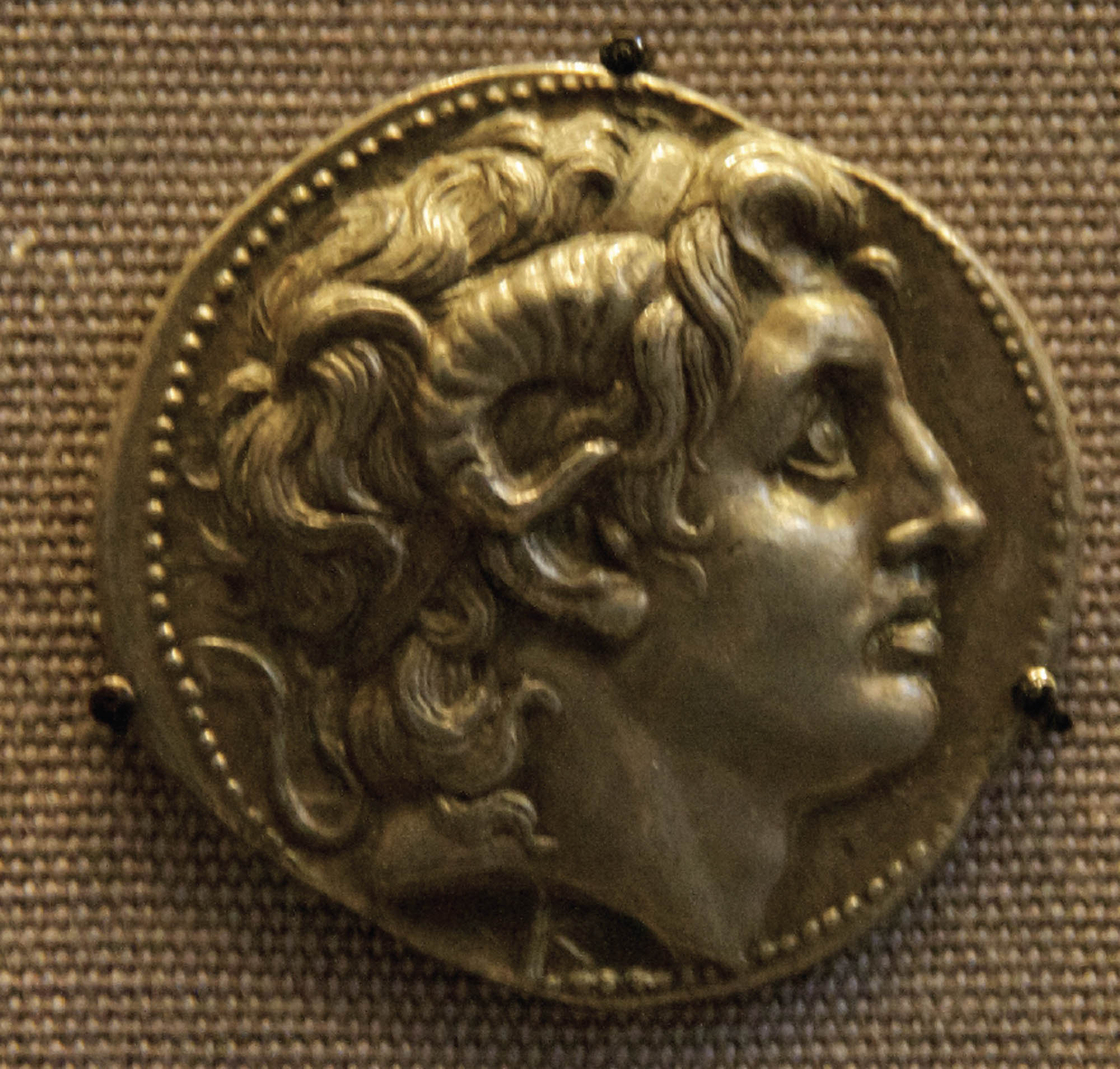 A coin features a detailed profile of Alexander the great. 