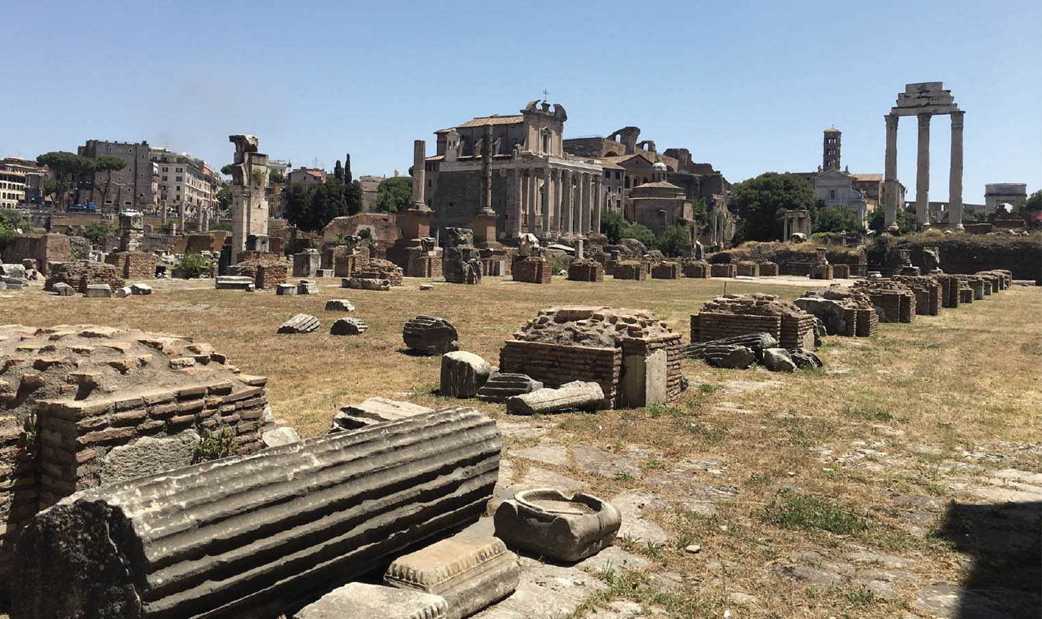 Photo of the ruins of the Roman Empire. Most of the structures shown in this photo are completely broken down, with small brick structures or scattered stones remaining.