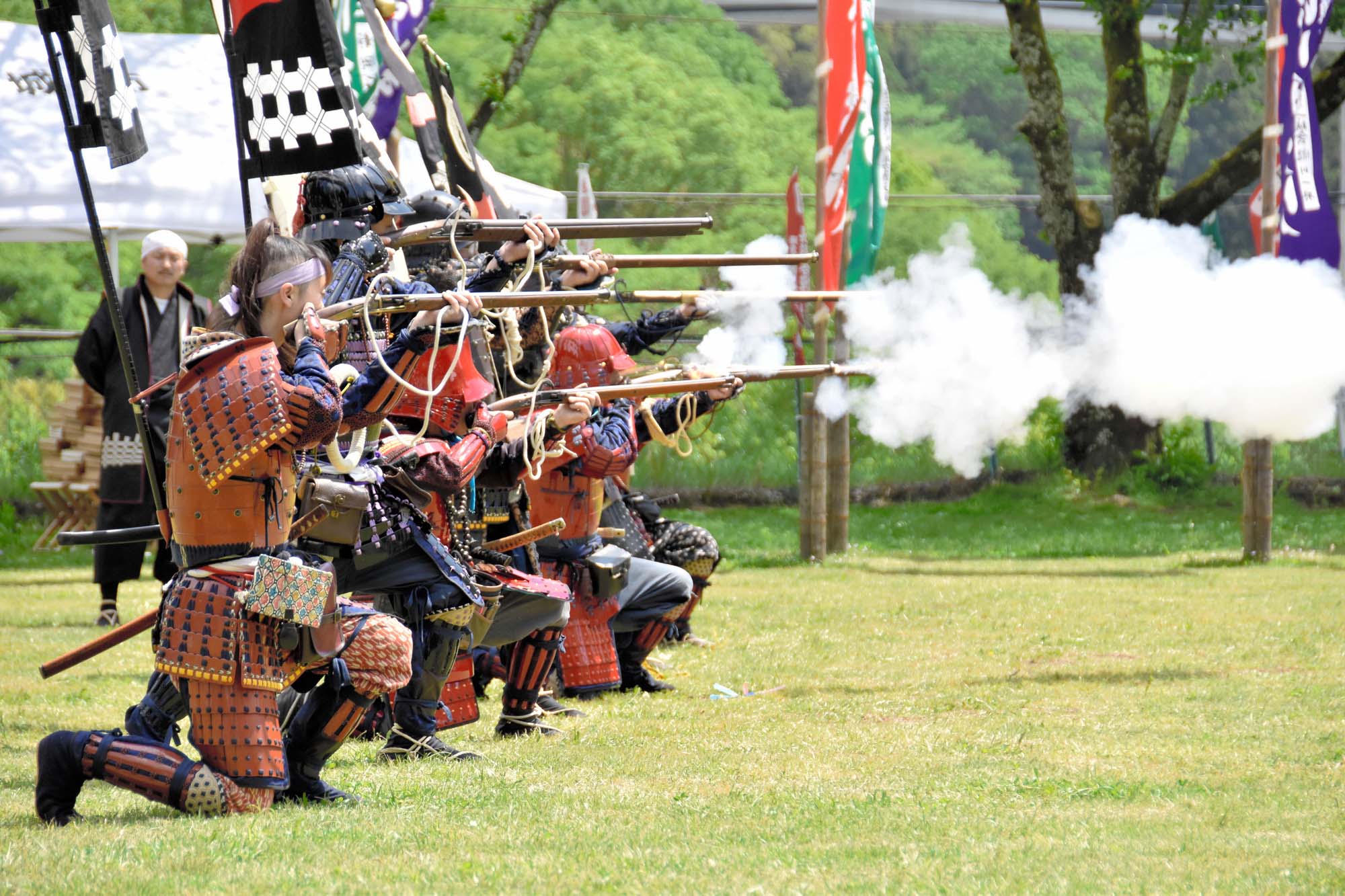 Photo of Japanese soldiers wearing traditional uniforms, firing guns in an open field.
