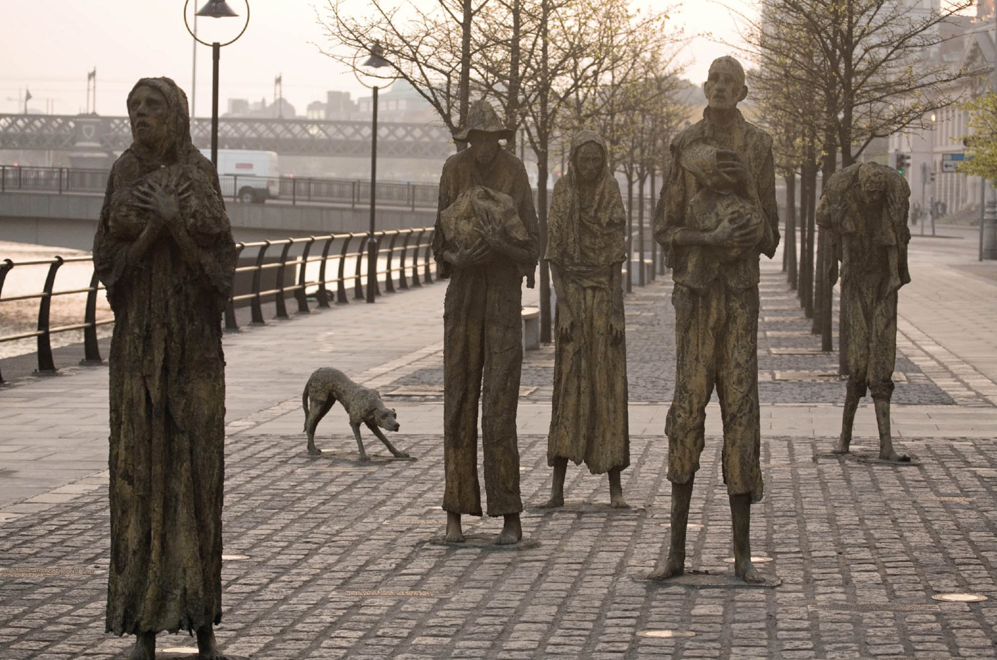 Sculptural installation honoring victims of the Irish famine. A group of malnourished peasants, dressed in rags stand in a street with expressions of agony. 