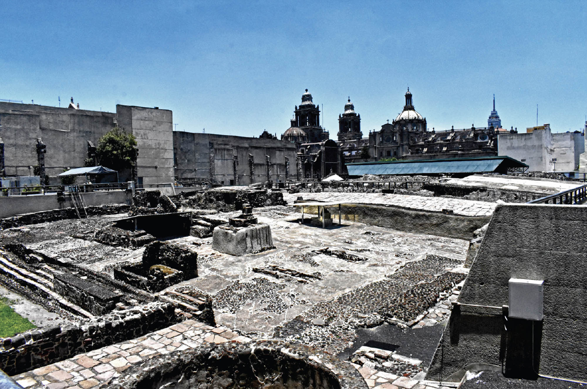 Photo of ruins of brick and stone structures. In the background is a great cathedral topped with tall steeples.