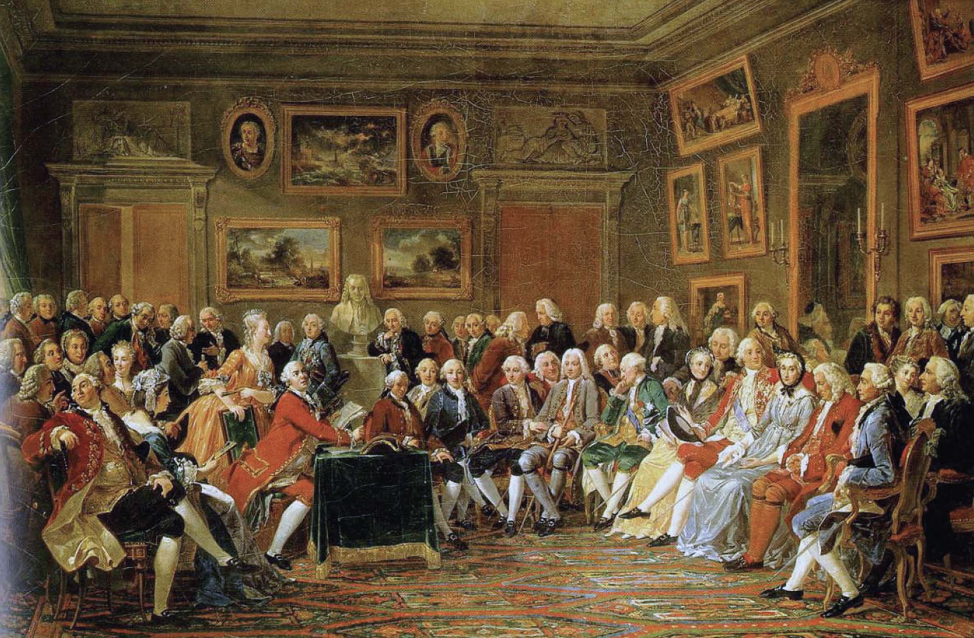 A painting of a salon depicts large group of people sitting in a semi-circle facing one another, in conversation. They sit in a richly-colored room with art-covered walls.