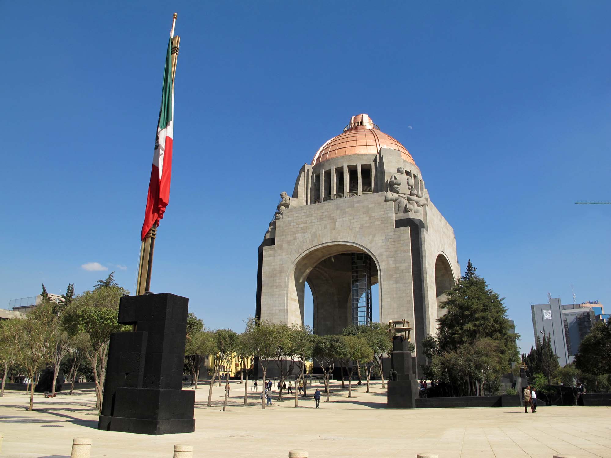 Modern-day photograph of a dome-shaped monument with a flag in front of it.
