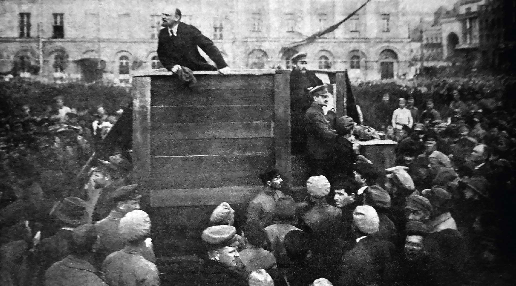 Photograph of Lenin, standing on a platform, with crowds of people surrounding him as he speaks. The painting used as the cover image looks to be modeled off of this photograph.