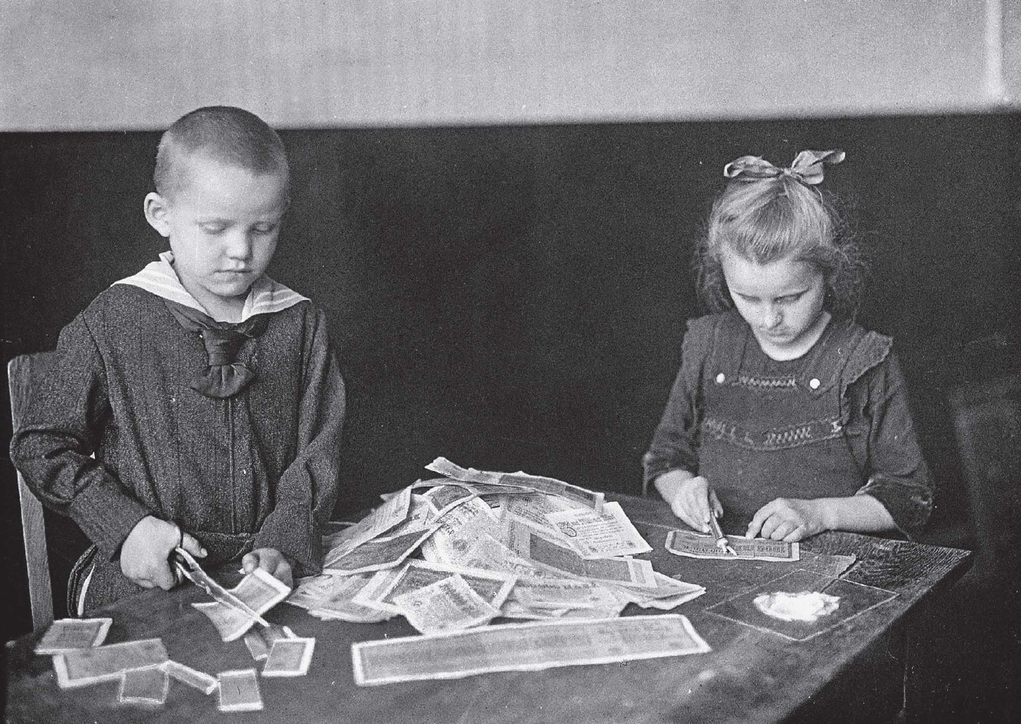 Children making crafts with banknotes, cutting and gluing. 
